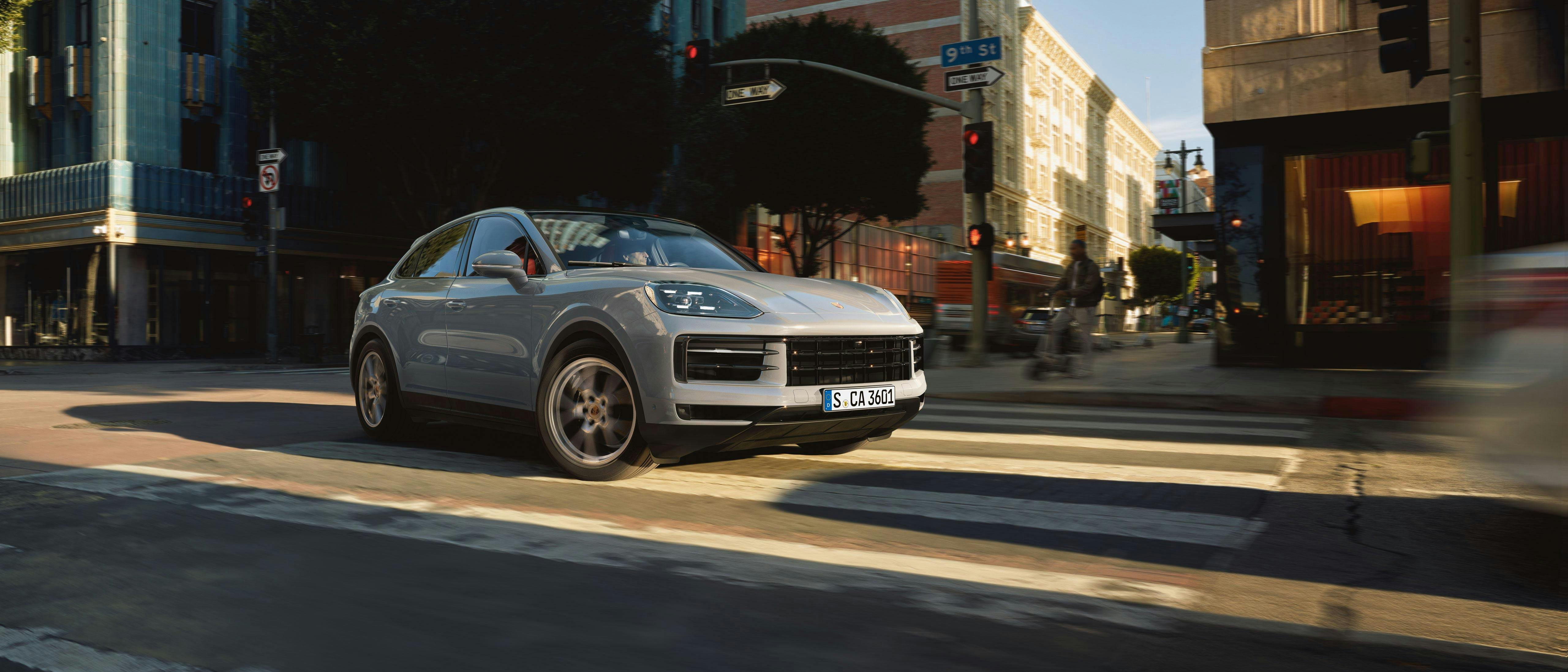 Grey Cayenne turning corner in urban environment