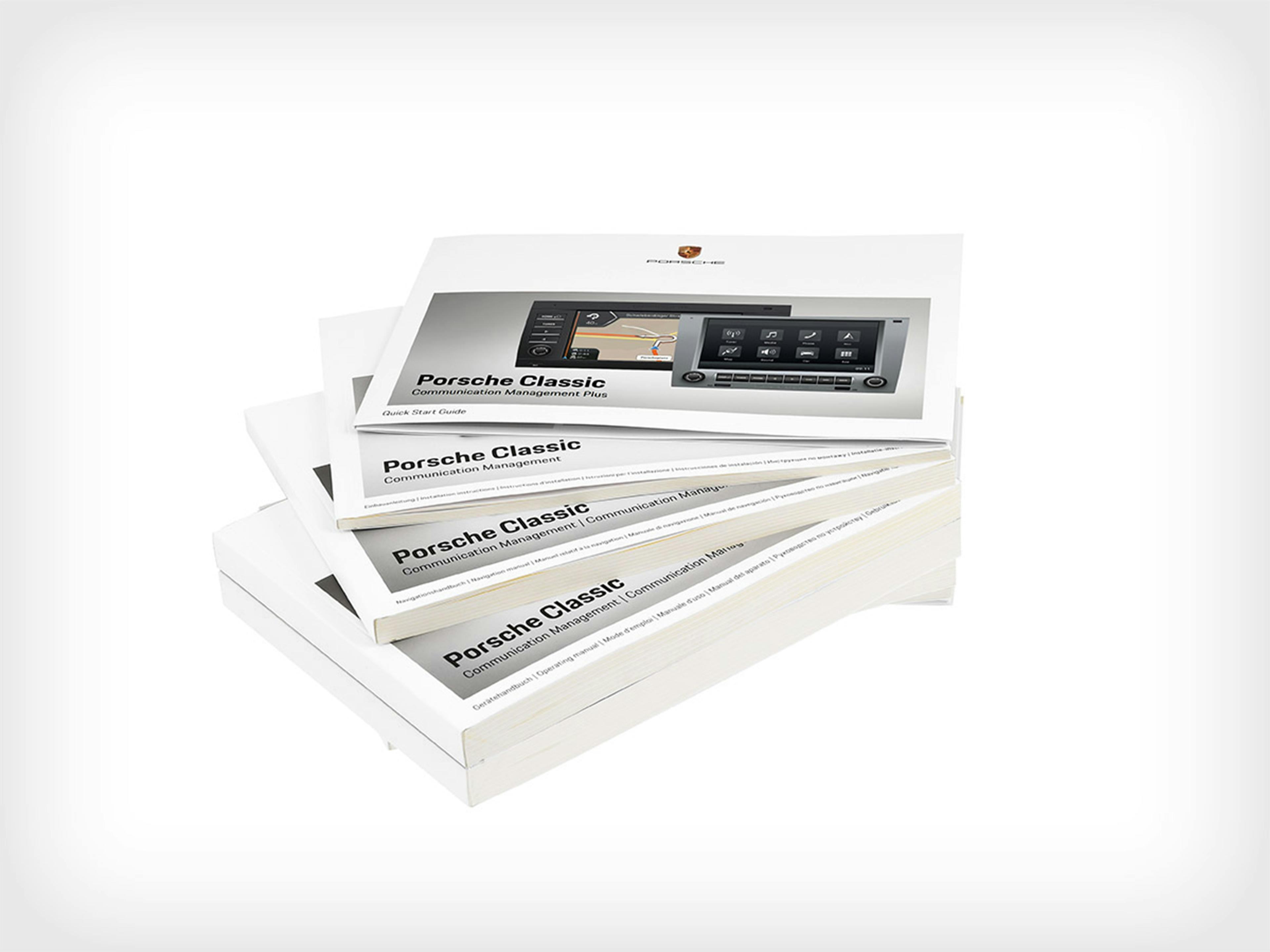 Several stacked operating manuals for the Porsche Classic Communication Management Plus.