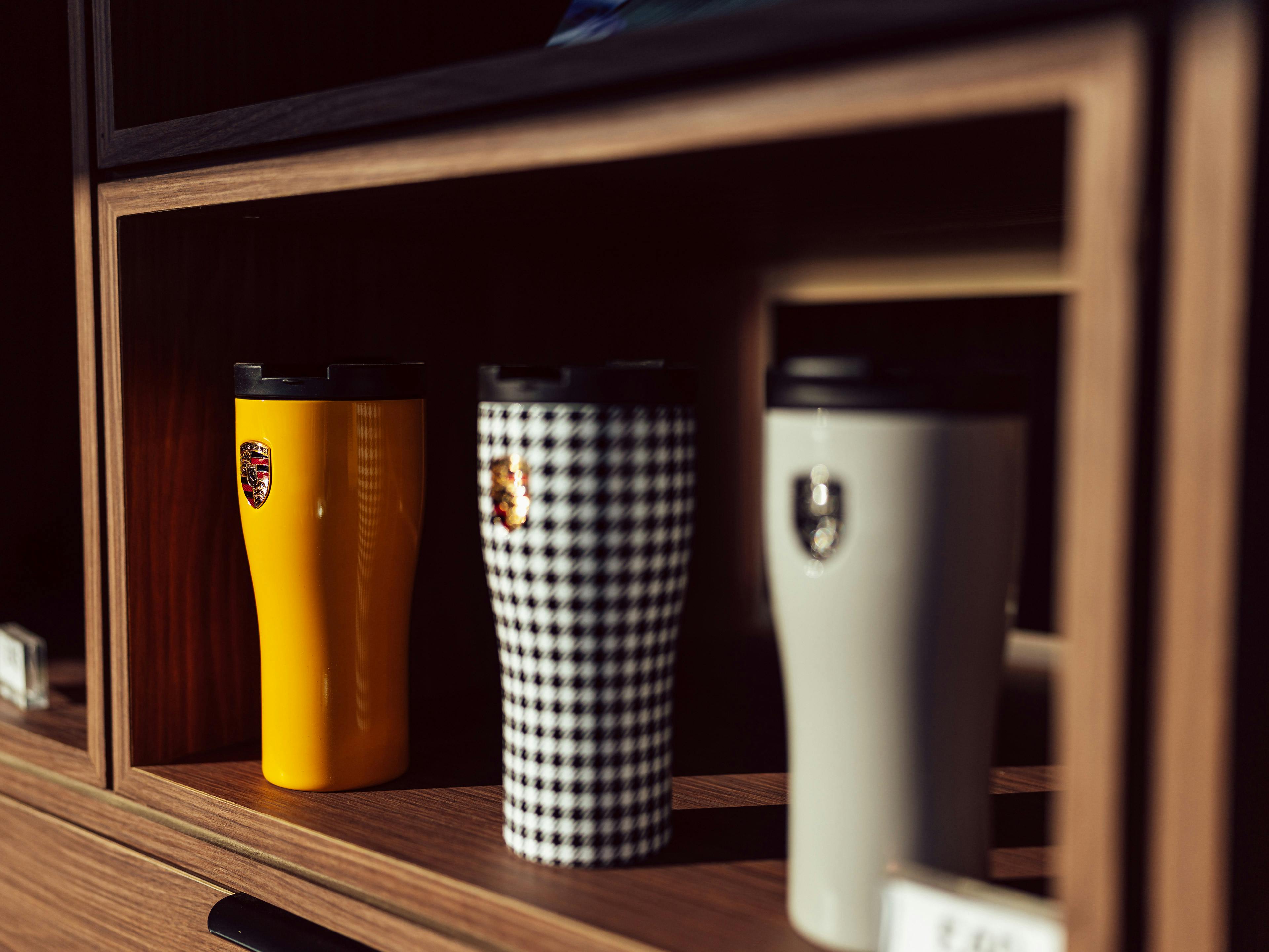 Porsche Lifestyle Shop shelf displaying yellow, checked and white branded flasks.