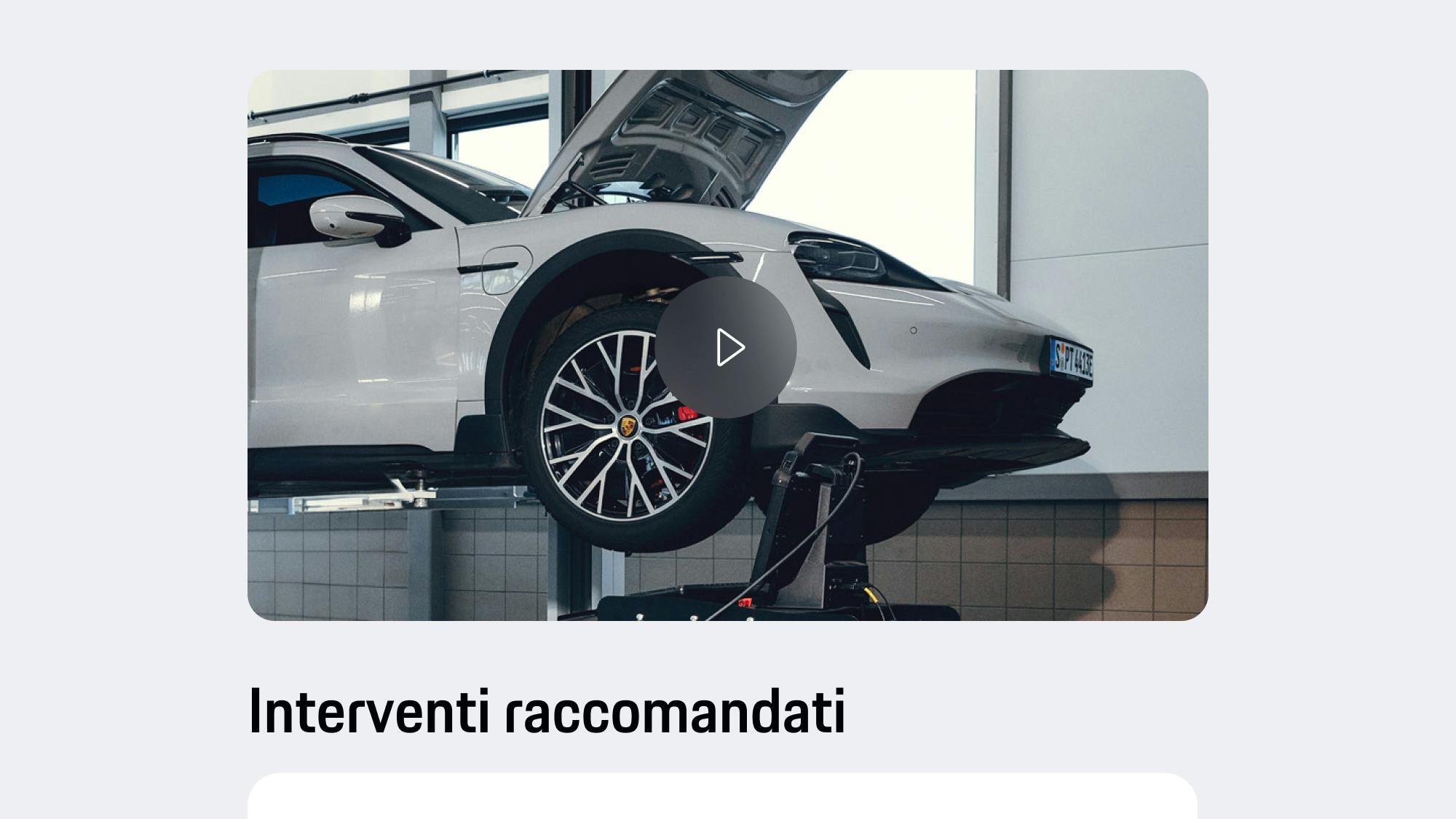 Vista dell'app che mostra una Porsche grigio chiaro su un ponte sollevatore con il cofano aperto, il pulsante di riproduzione video e il testo di raccomandazione visualizzato sotto.