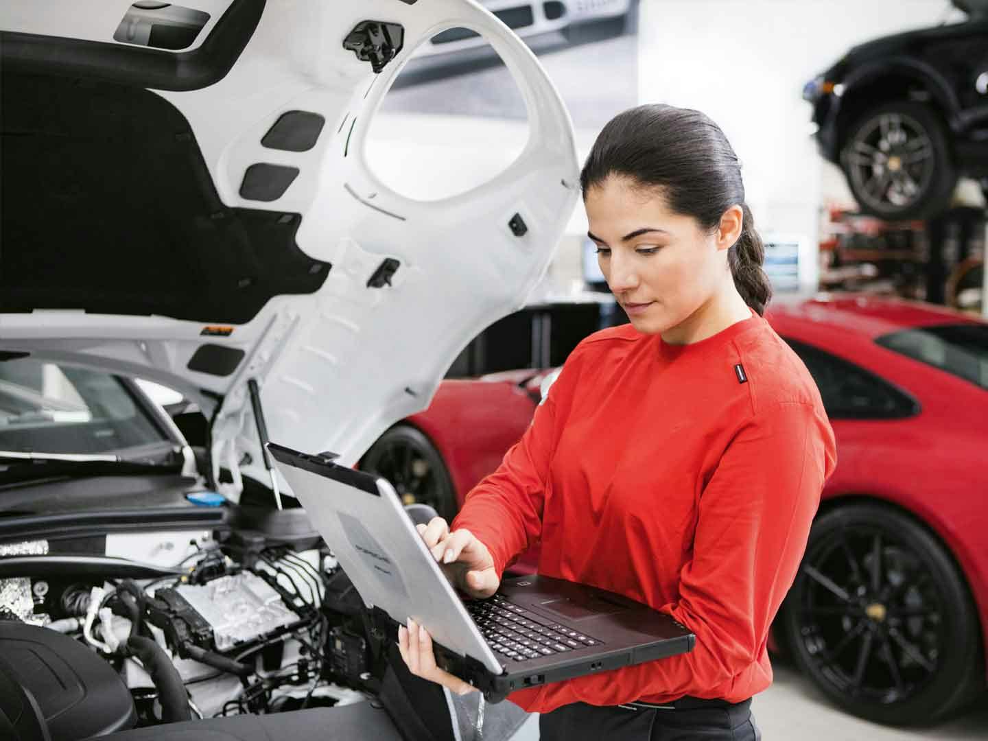 En kvinnlig mekaniker arbetar på en Porsche i ett Porsche Service Center.