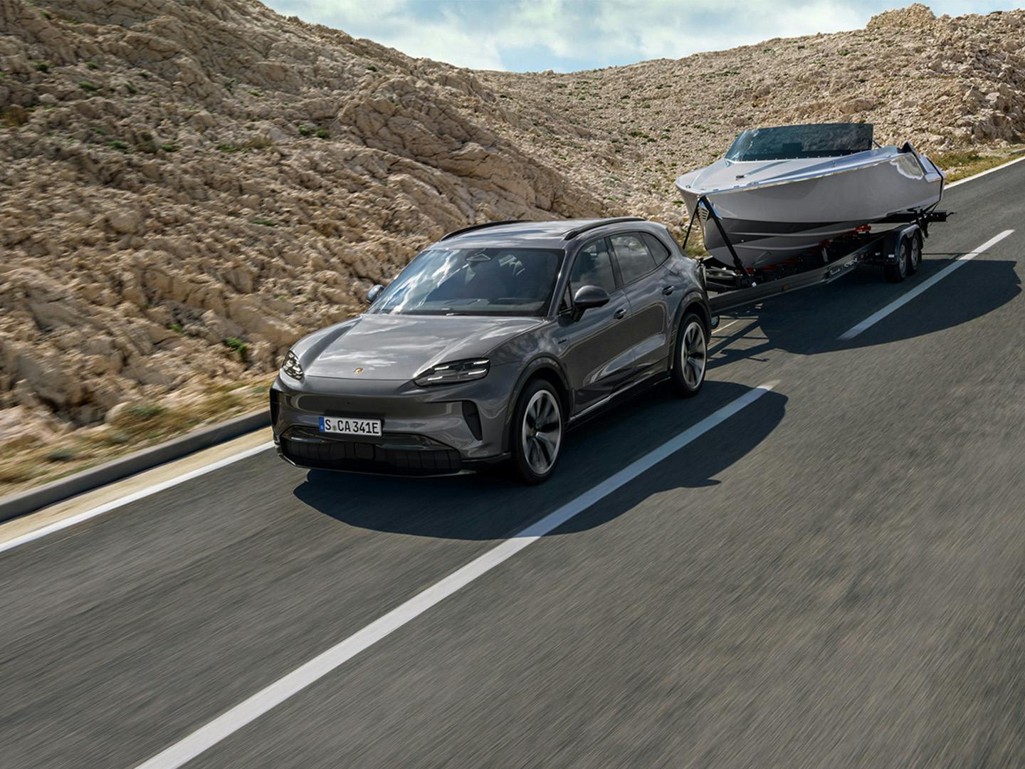 Porsche Cayenne Electric ρυμουλκεί σκάφος σε ανοιχτό δρόμο σε ορεινή διαδρομή (ρυμούλκηση σκάφους).