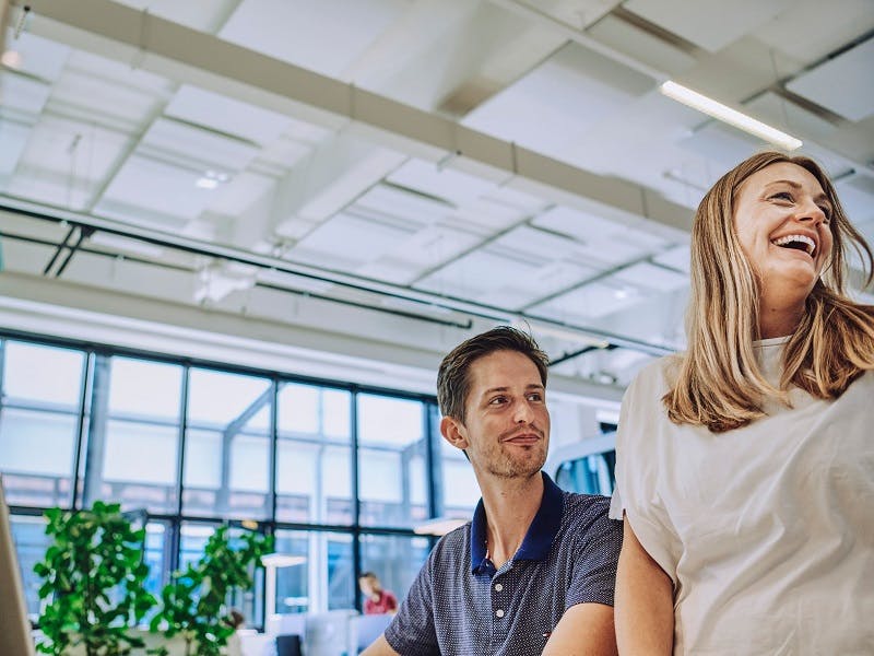 Two happy graduates at Porsche look to the side.