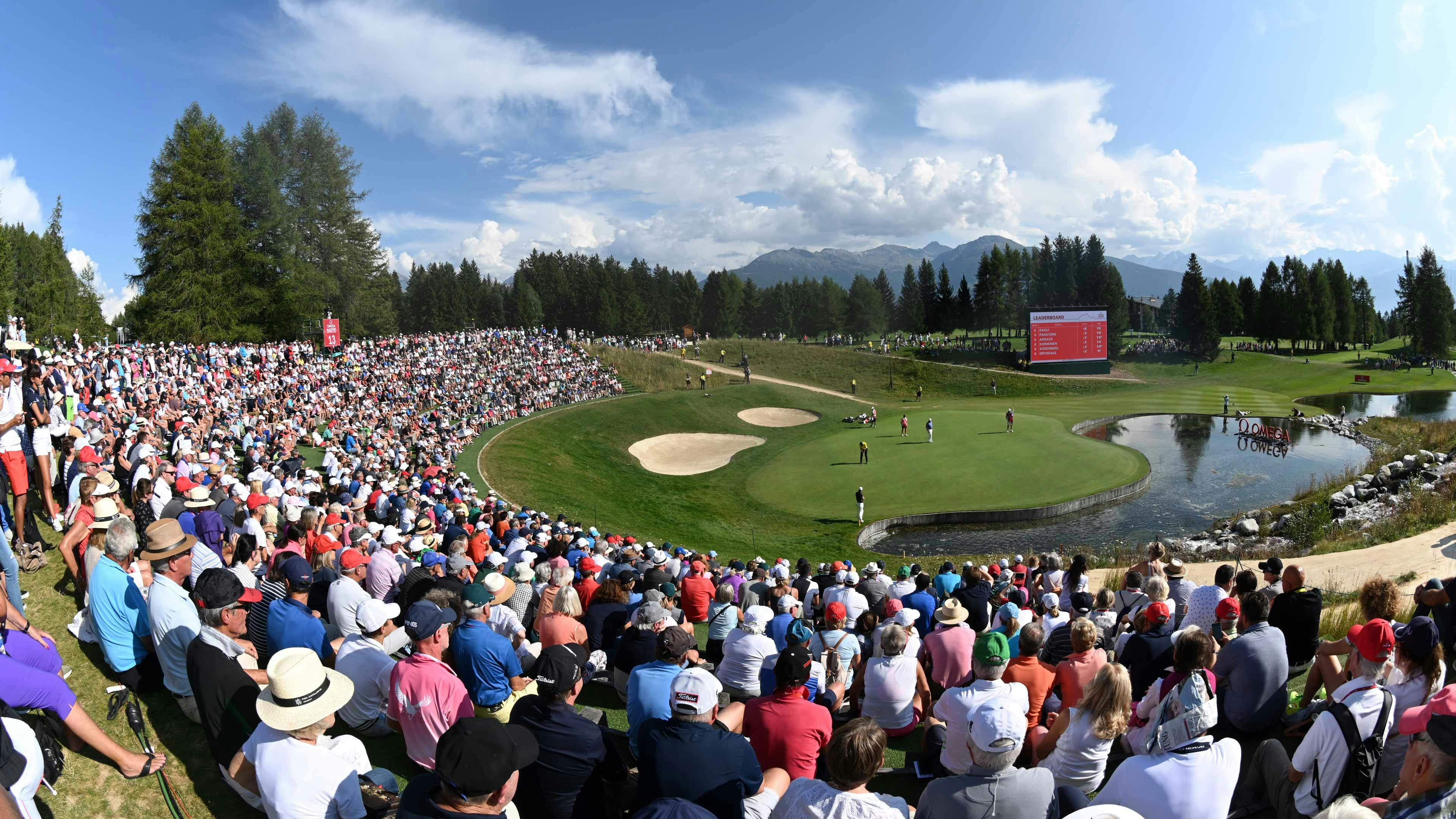 Der Golfplatz von Crans-Montana umgeben von Publikum und mehreren Golfspielern auf dem Course