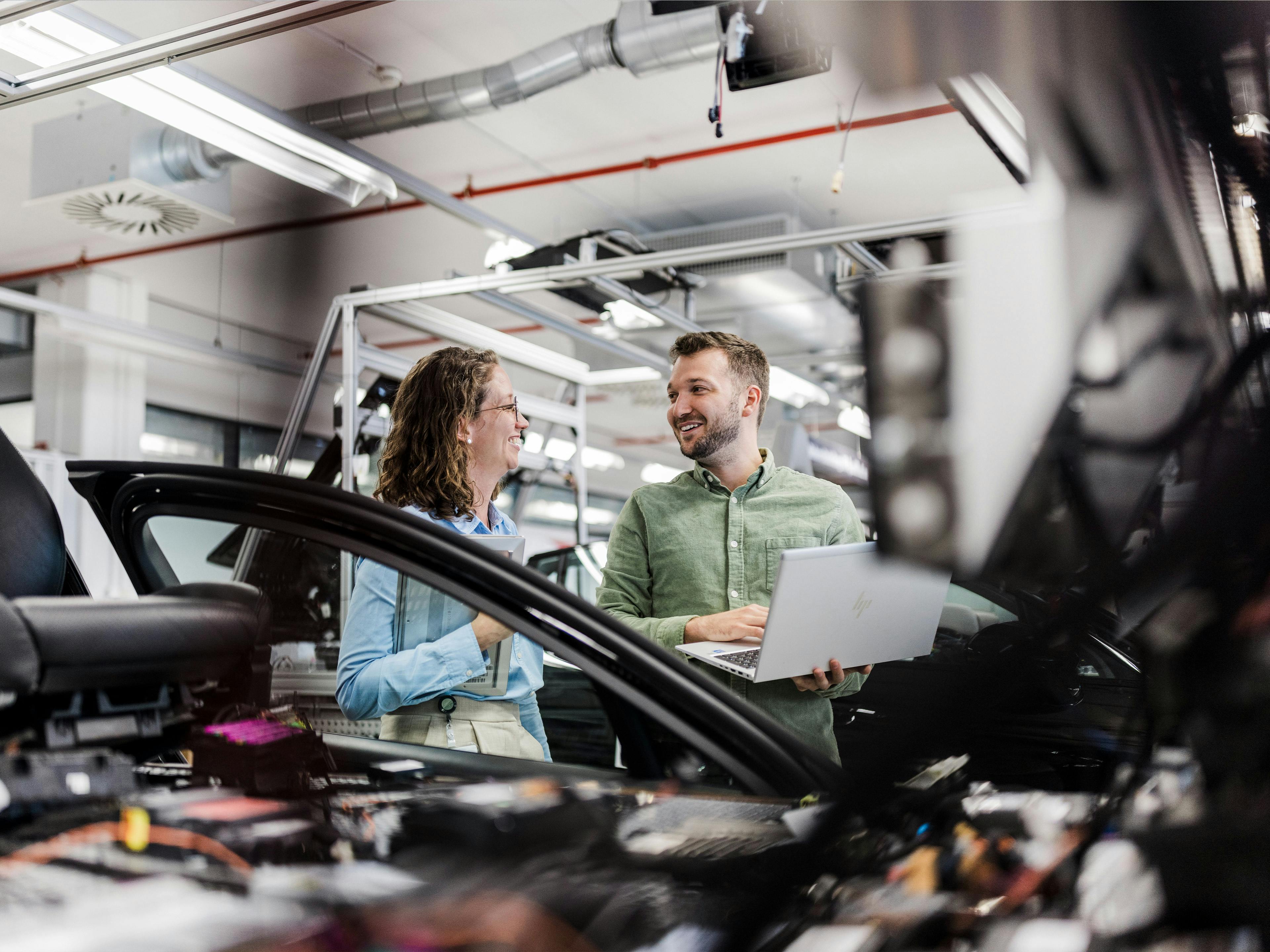 Eine Porsche Entwicklerin führt einen Kollegen durch den Prüfstand.