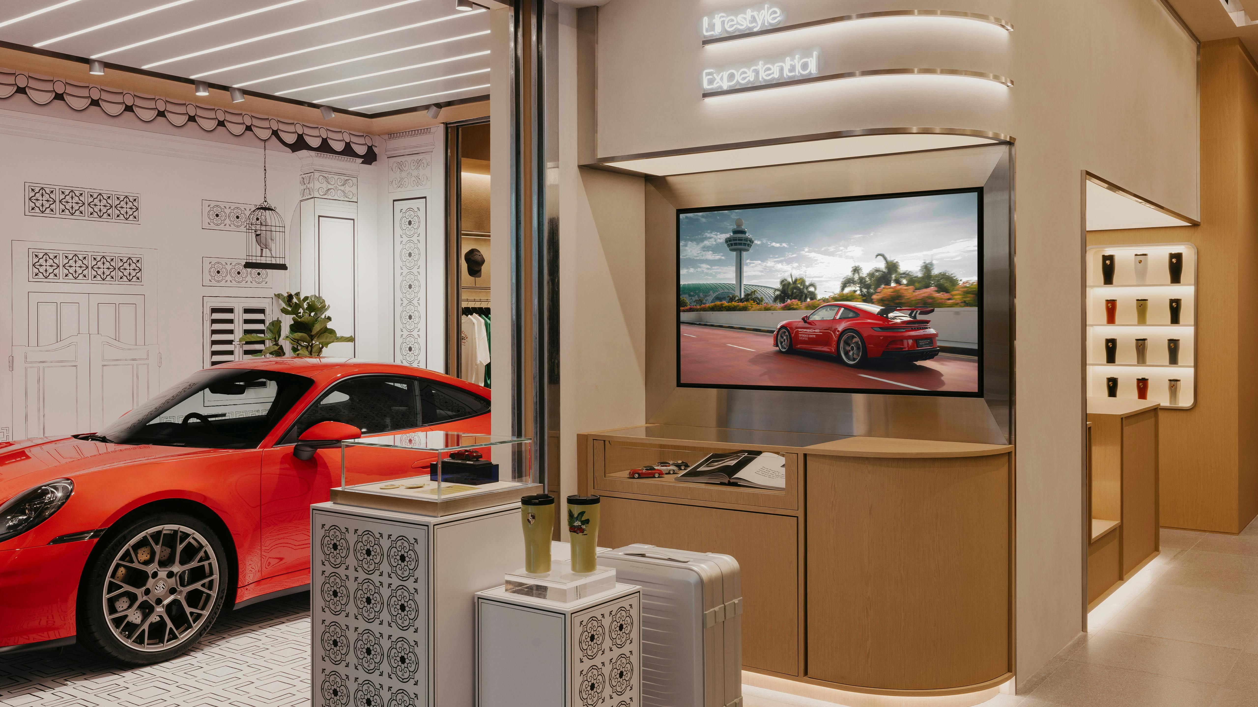 Screens and display stands with Porsche Products, featuring a portion of the Porsche Culture Garage with a red Porsche 911