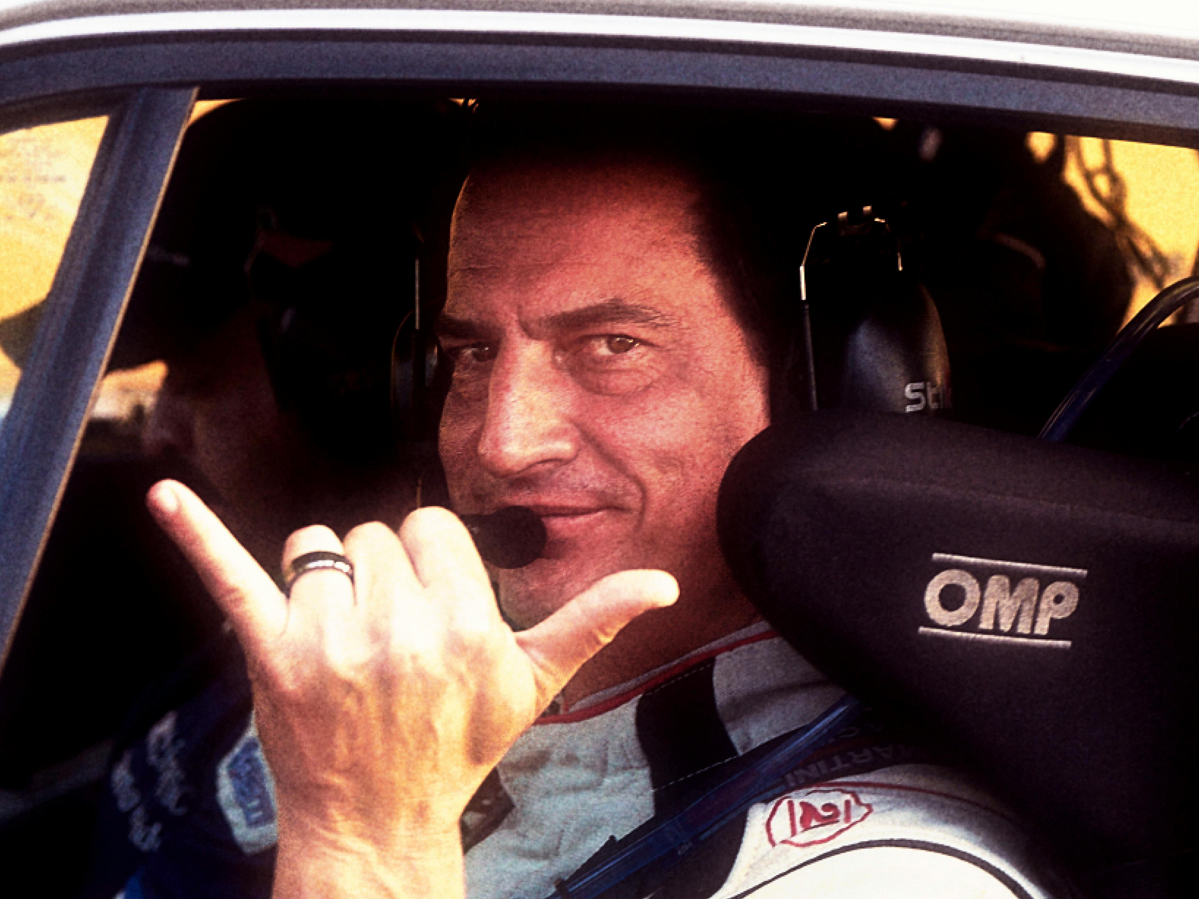 Cándano, piloto de carreras, sonríe desde el interior de su auto de carreras.