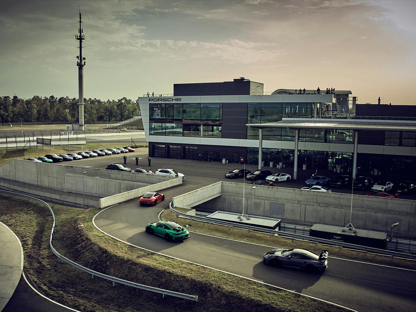 Mehrere Porsche Sportwägen auf der Teststrecke vor dem Porsche Experience Center am Hockenheimring.