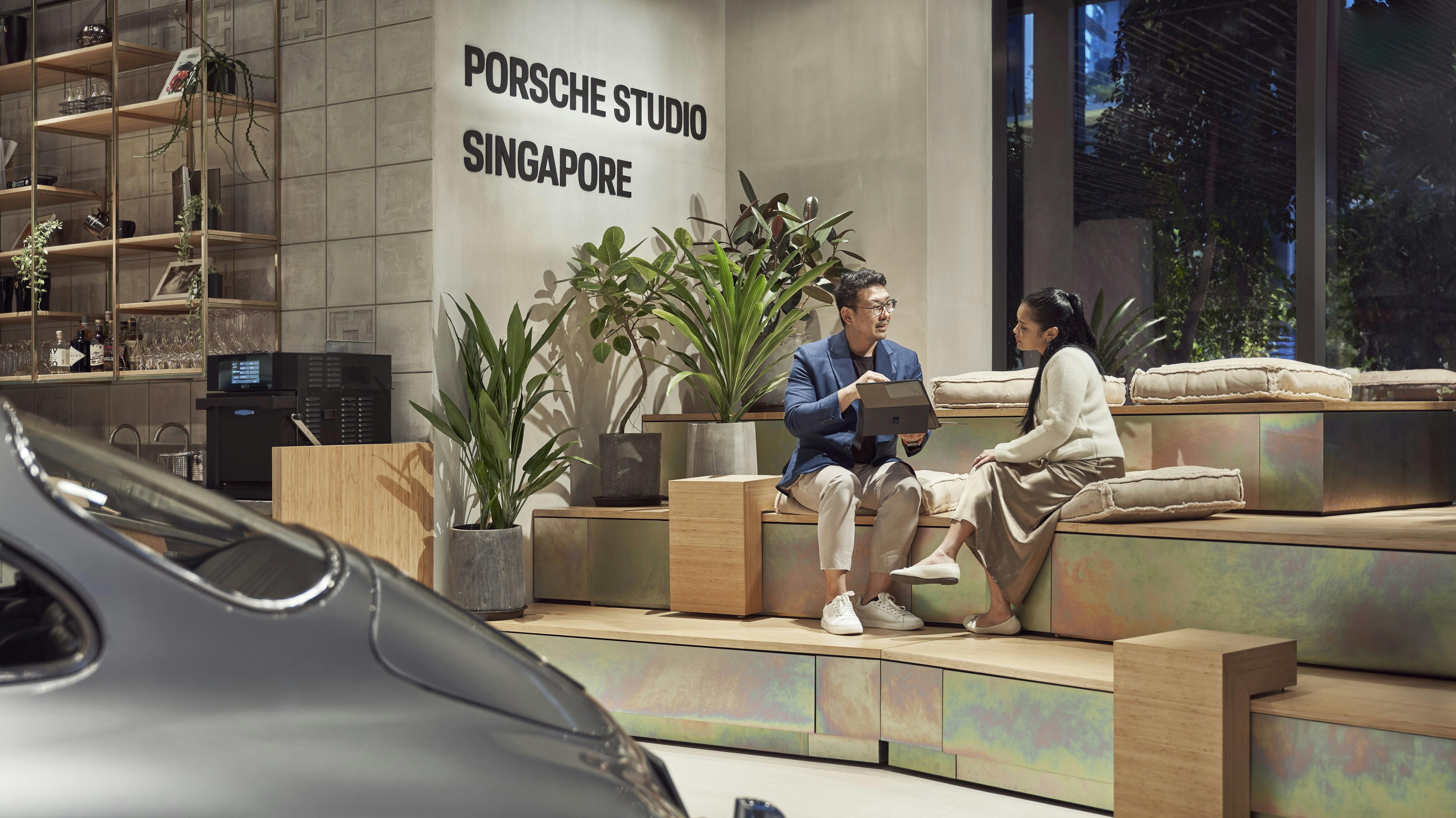 Tribune seating area at Porsche Studio Singapore, with a Porsche Consultant assisting a customer while seated.