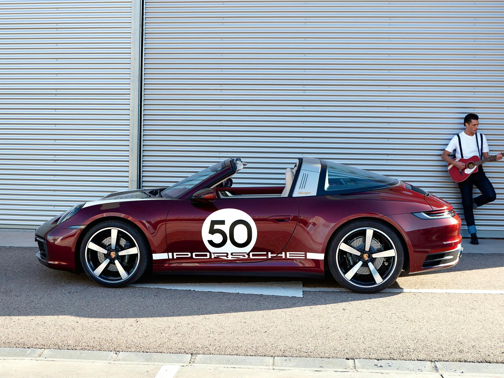 Porsche 911 Targa 4S Heritage Design Edition in Cherry Metallic. Side view. A man with a guitar is in the background.