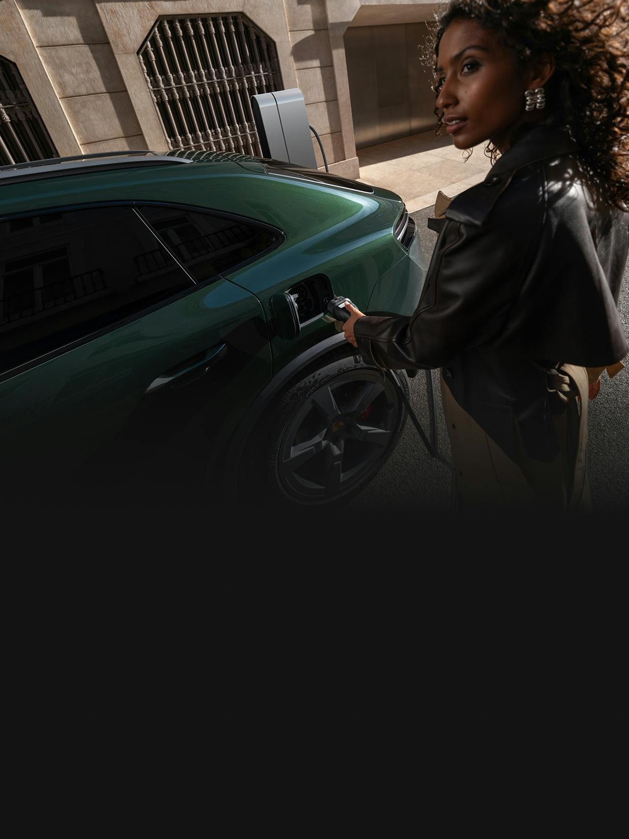 A woman plugging a charging plug into the charging socket of a Porsche Macan 4S.