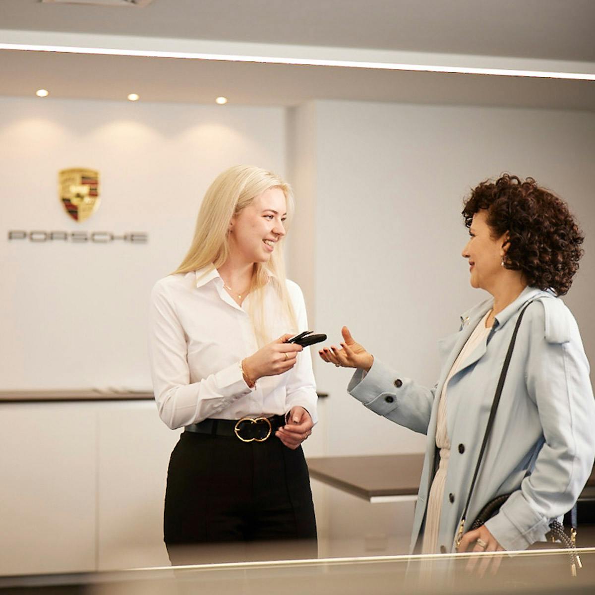 A Porsche employee handing over a car key to a customer.