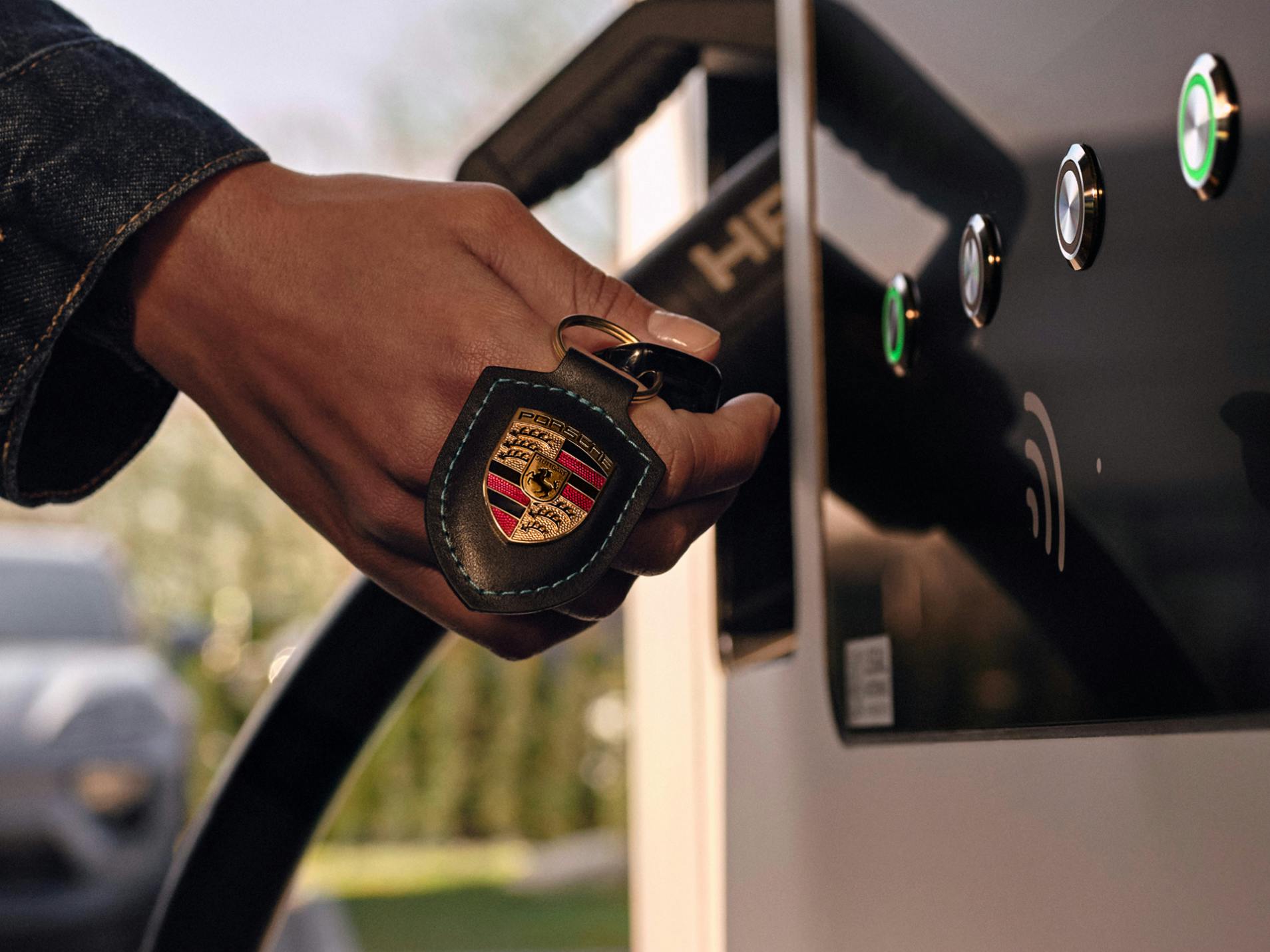 The key of a Porsche being held in front of a charging pedestal.