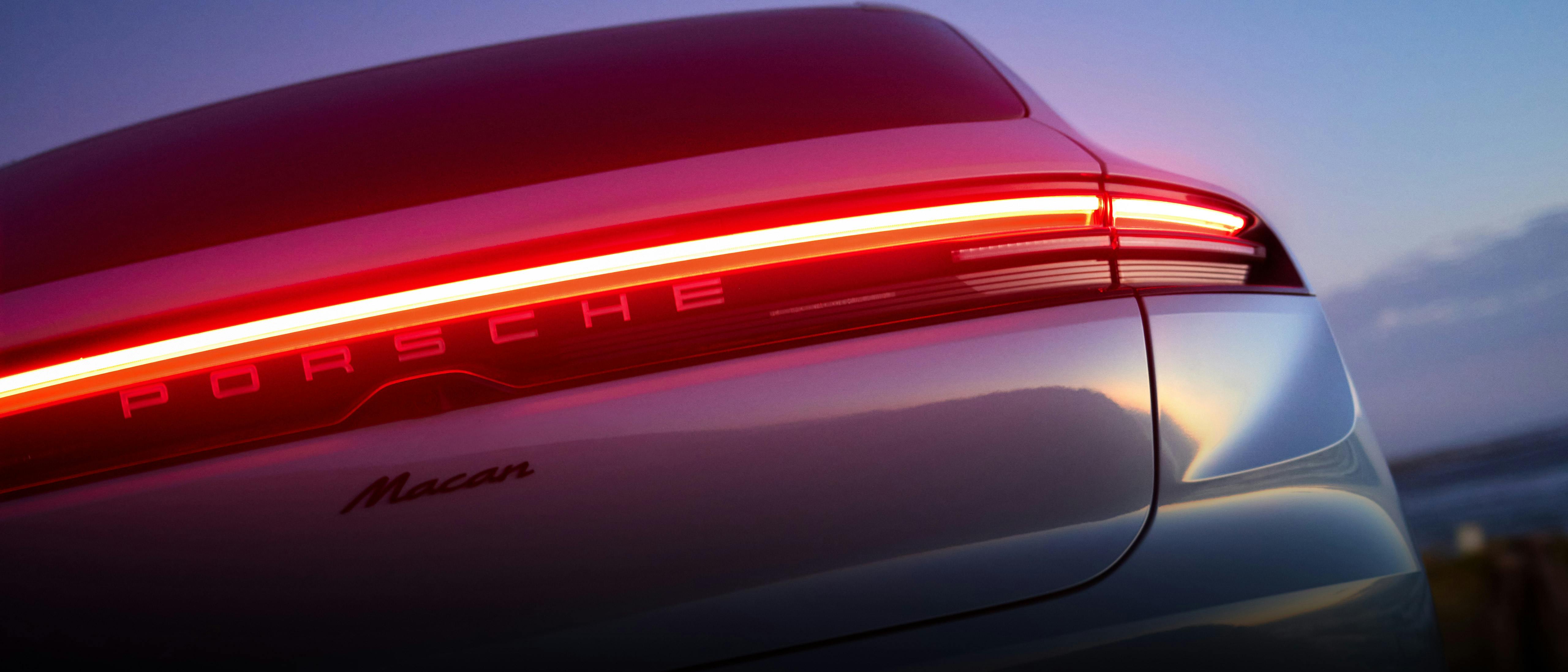 Close-up of the rear of a silver Porsche Macan with illuminated red taillights.