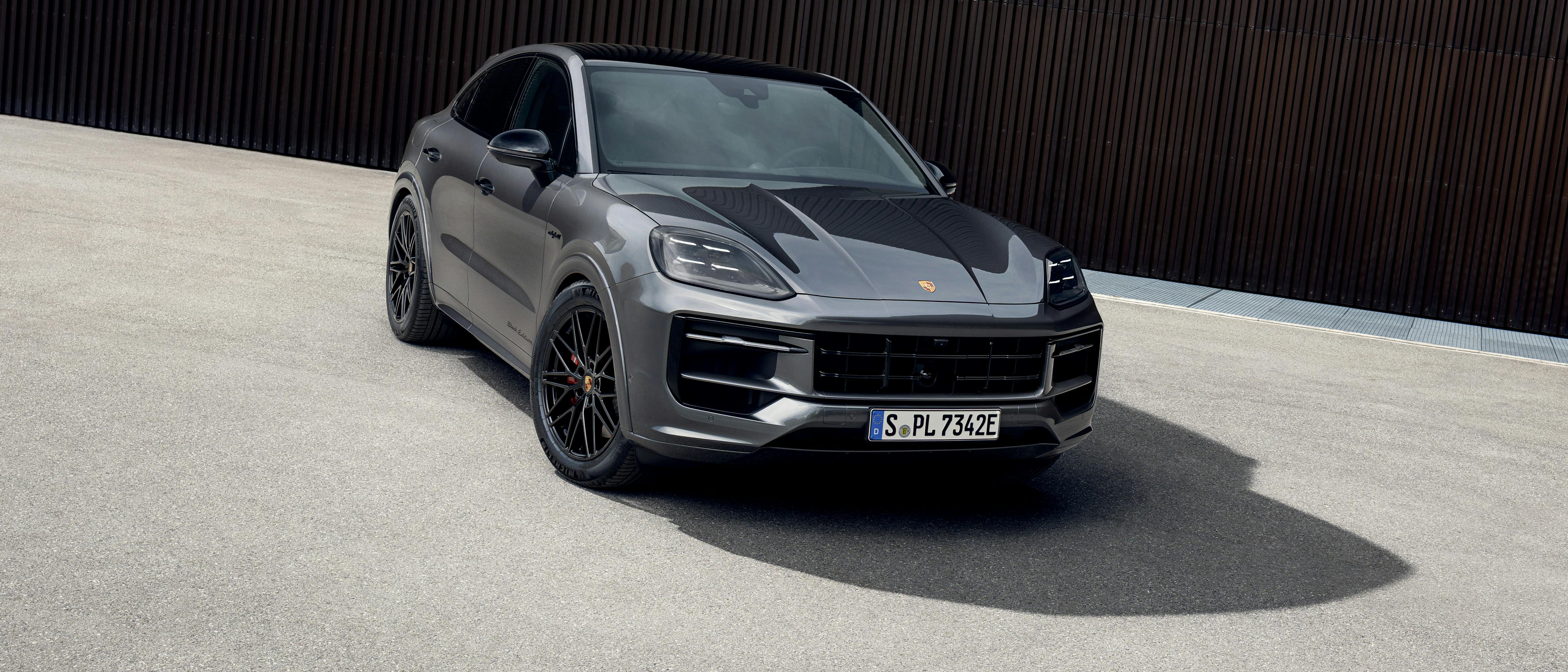 The Cayenne S E-Hybrid Coupé Black Edition parked outside a tall brown building.
