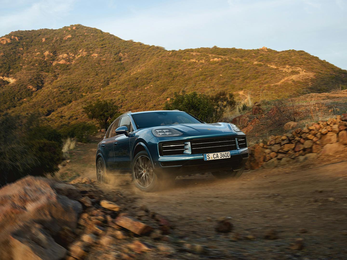 Porsche Cayenne rijdt offroad door de bergen.
