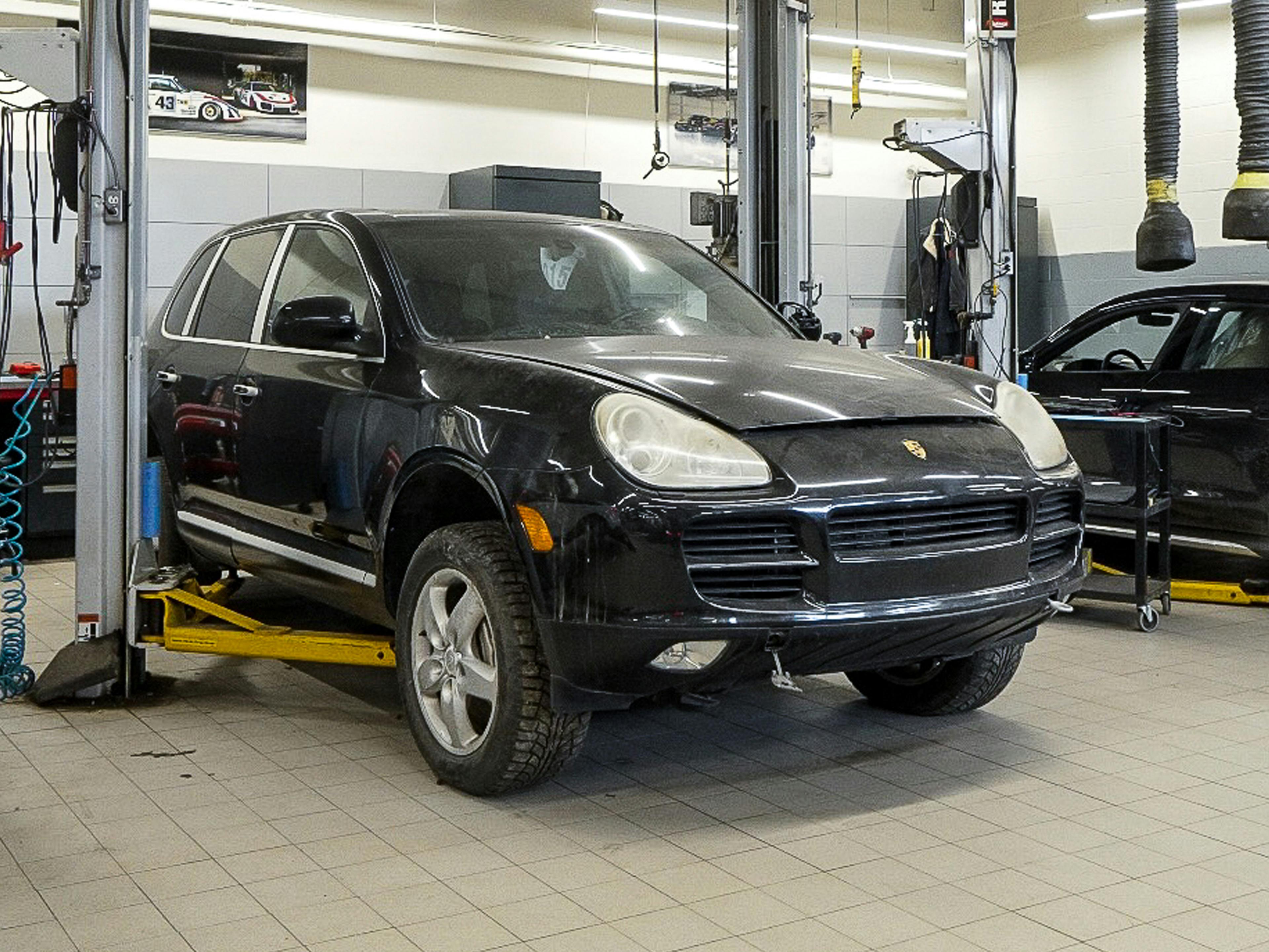 Prestige – A black Porsche Cayenne elevated in a service bay.