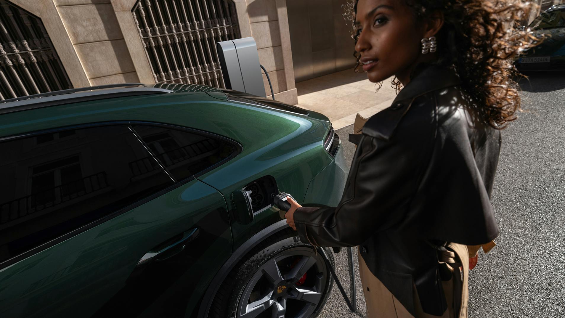 A woman plugging a charger into the charging port of the Porsche Macan 4S.