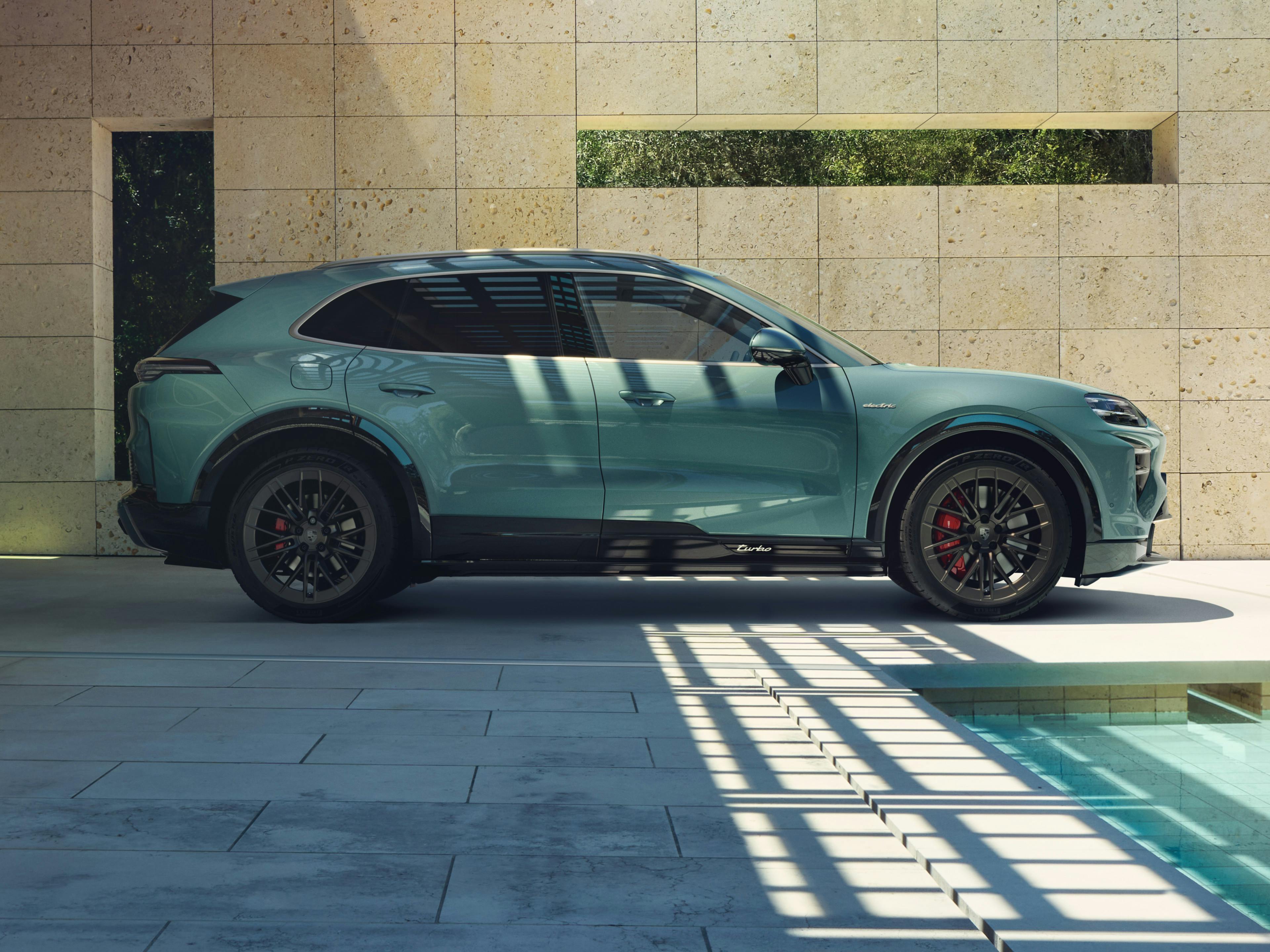 The Cayenne Turbo Electric SUV parked in a vibrant, modern environment, with a pool nearby.