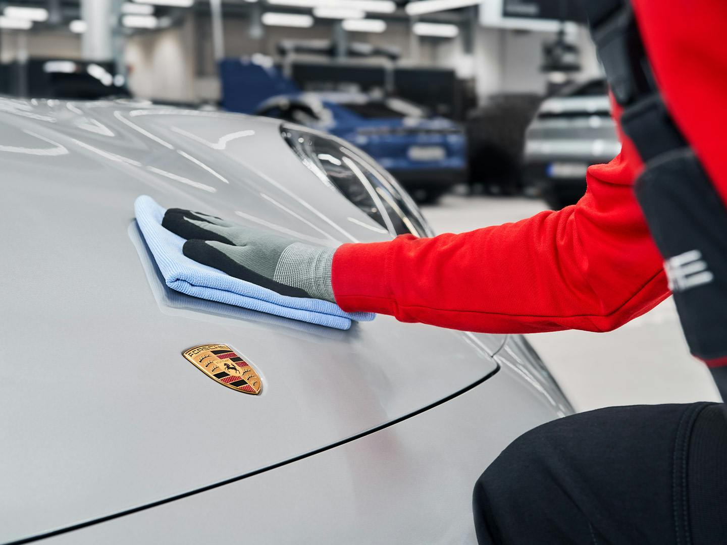 A Porsche employee cleans the hood of a Porsche with a cloth.