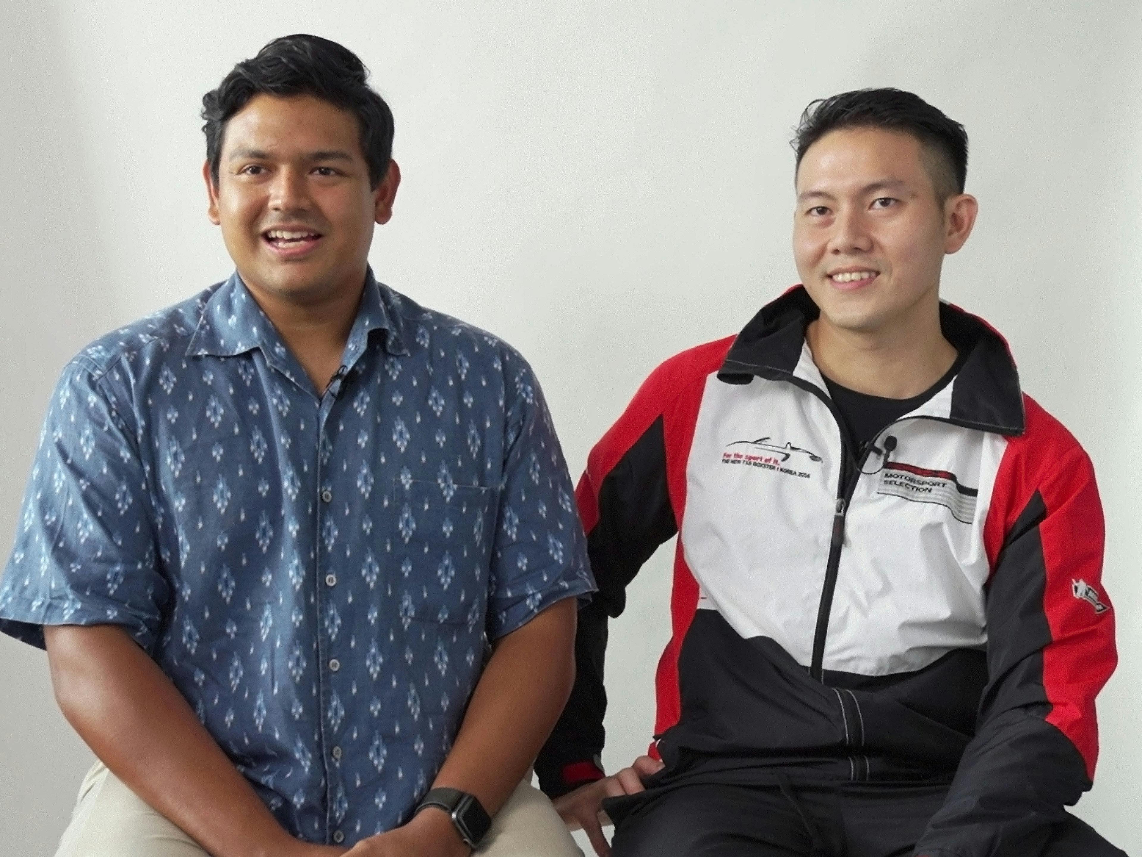 Porsche employees Riaz and Russel sitting in front of the camera in an interview and smiling.