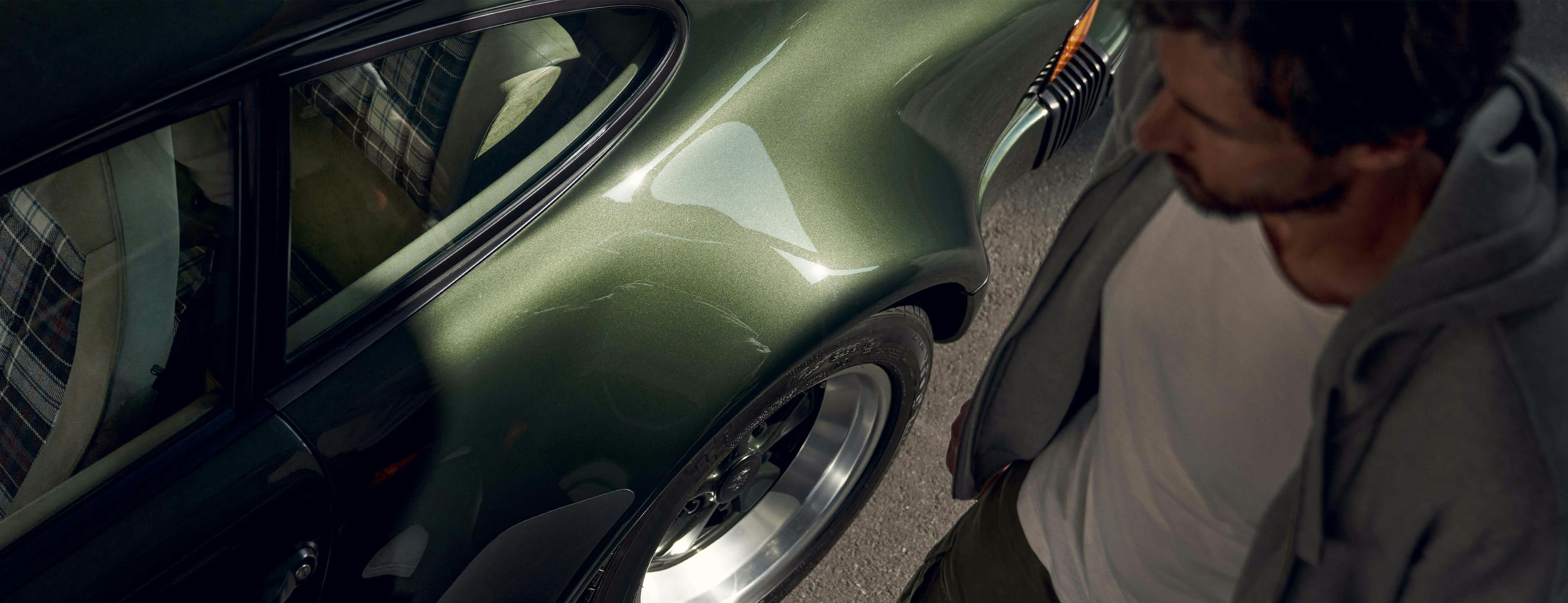 Man standing next to a dark green Porsche 911 G-model