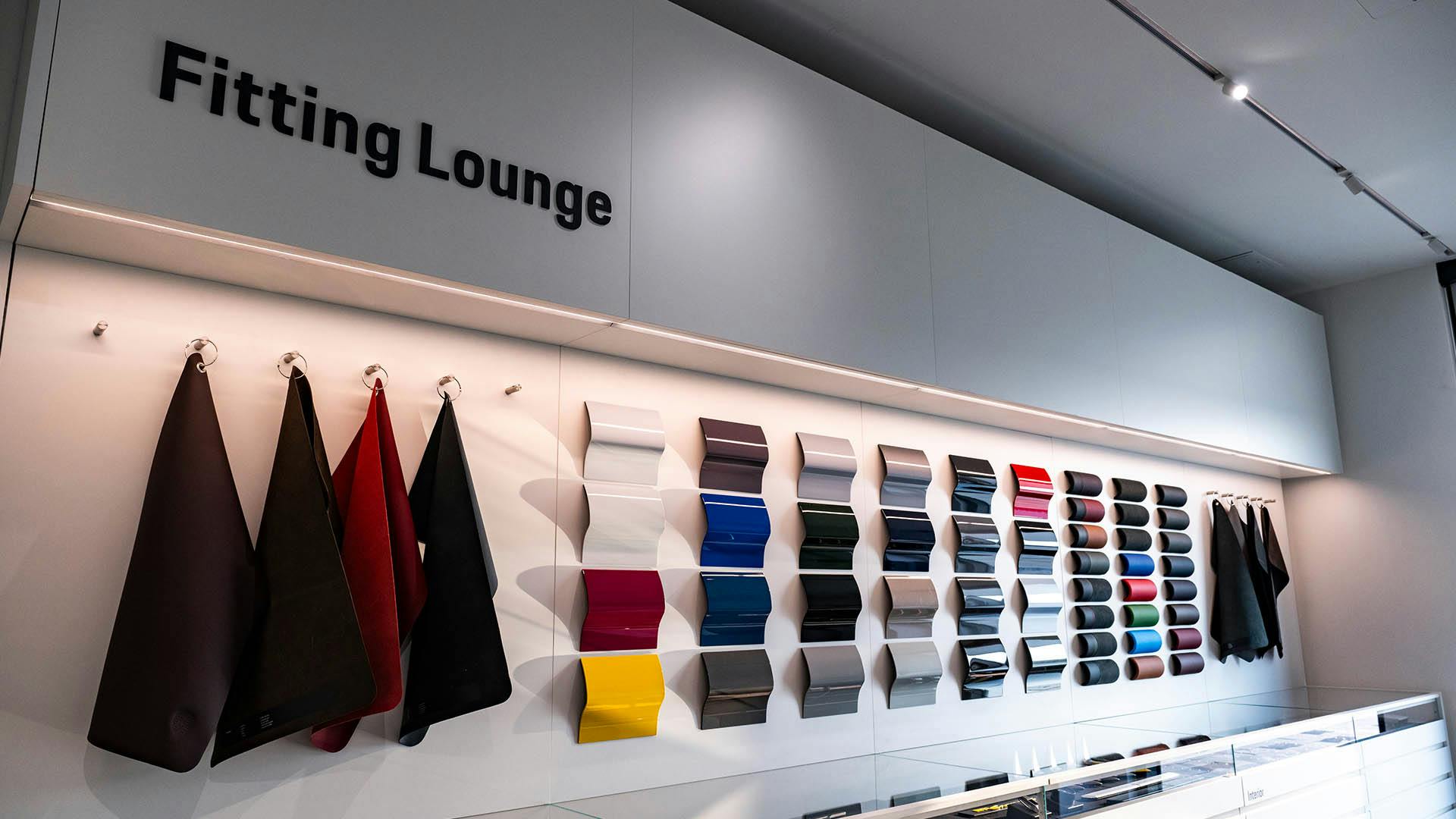 Une photo d'un salon d'aménagement Porsche, avec différentes options de cuir et de peinture automobile affichées au mur. ​