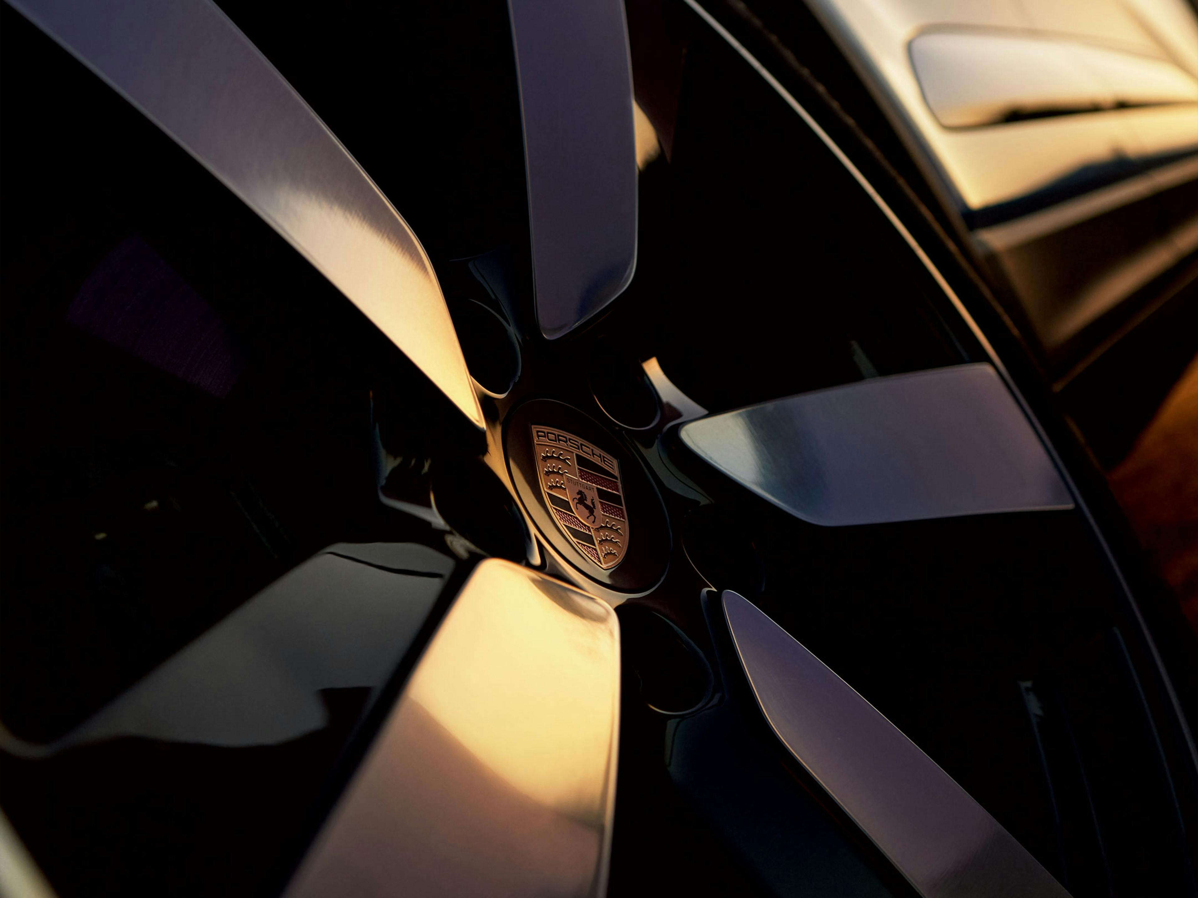 Closeup of Porsche crest on a wheel at sunset.