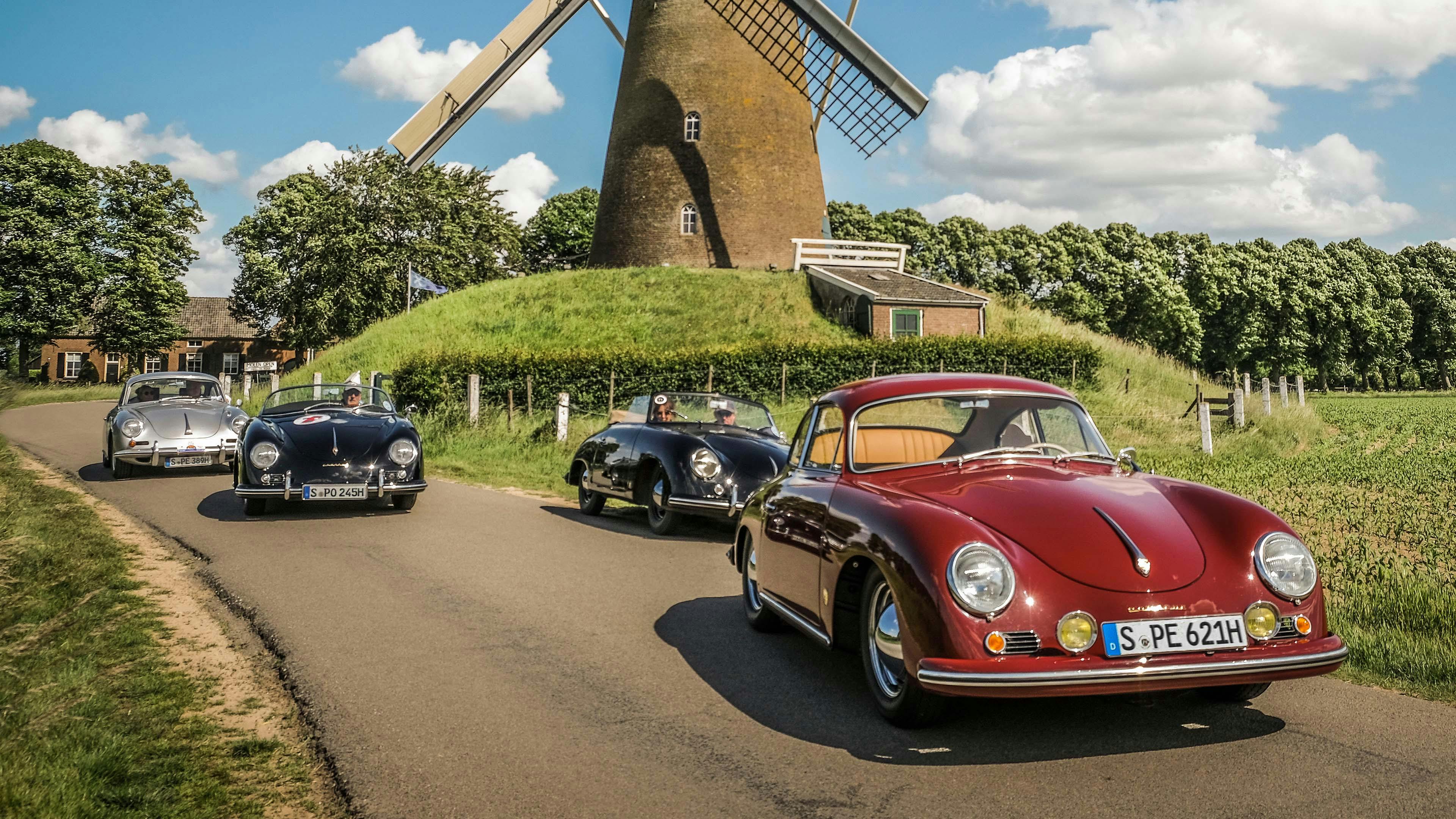 4 Porsche modellen rijdend achter elkaar voor een molen.