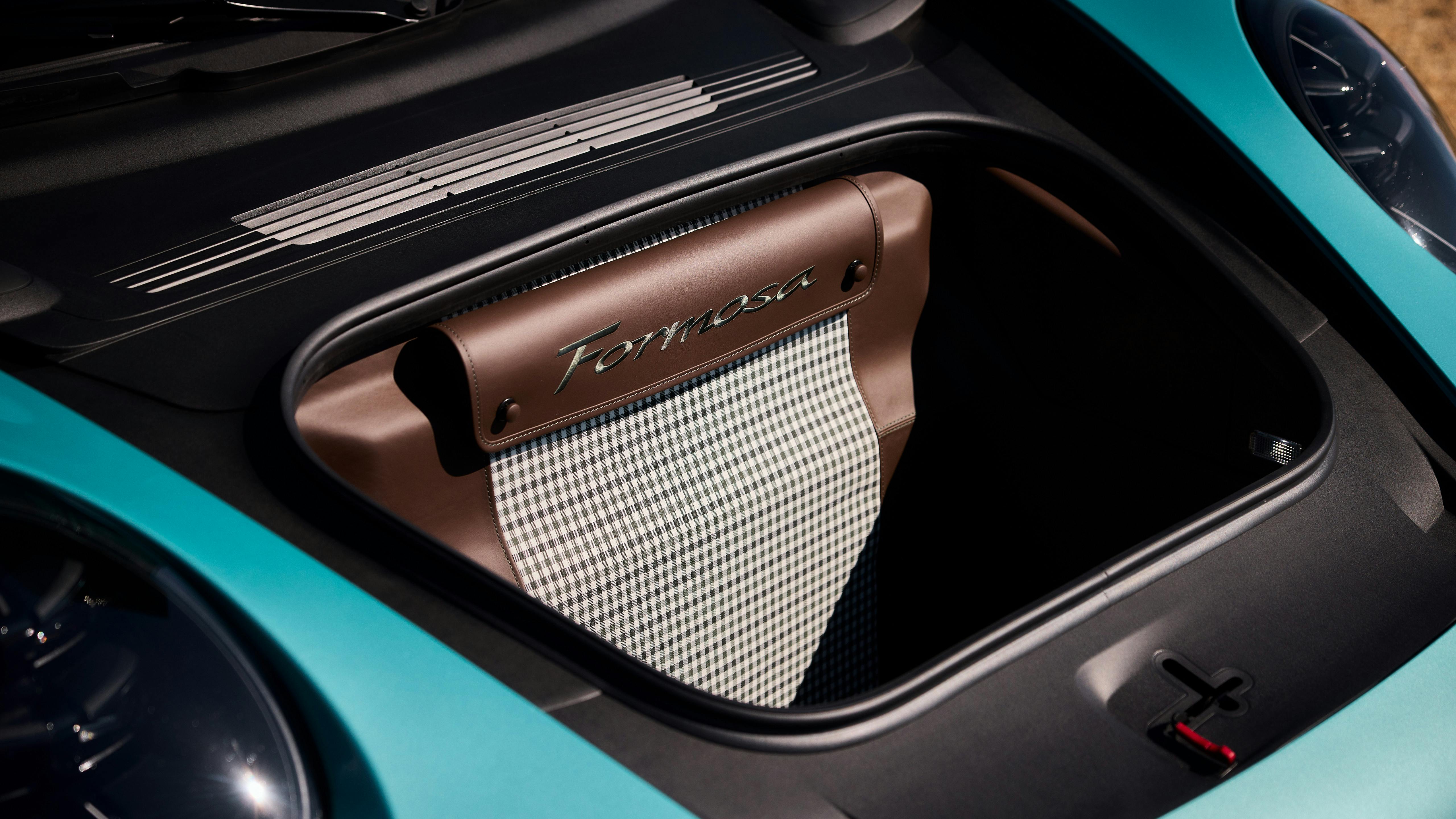 Detail of a Porsche 911 Carrera luggage compartment with brown leather panel, “Formosa” text and check pattern.