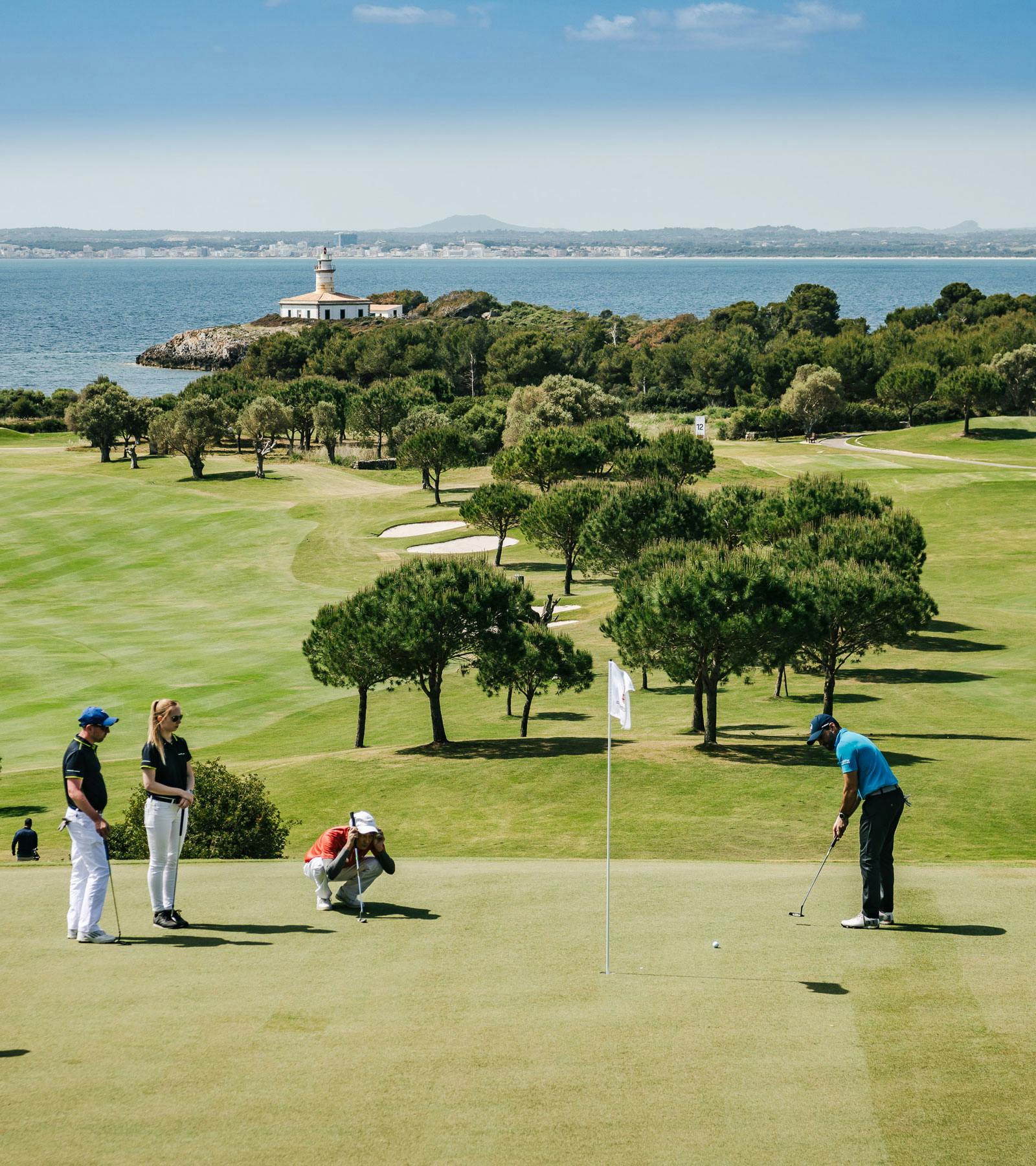 Vier Golfspieler auf dem Club de Golf Alcanda beobachten einen anderen Spieler beim Putten