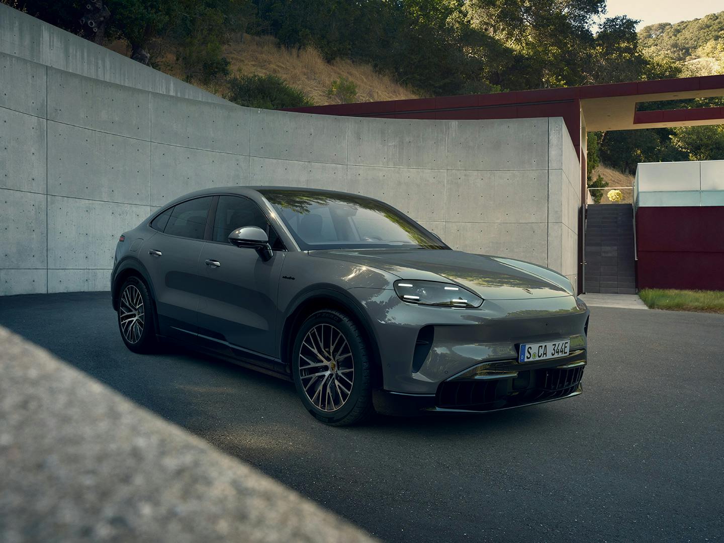 Ein Porsche Cayenne Electric steht auf einer Einfahrt vor einem minimalistischen Haus