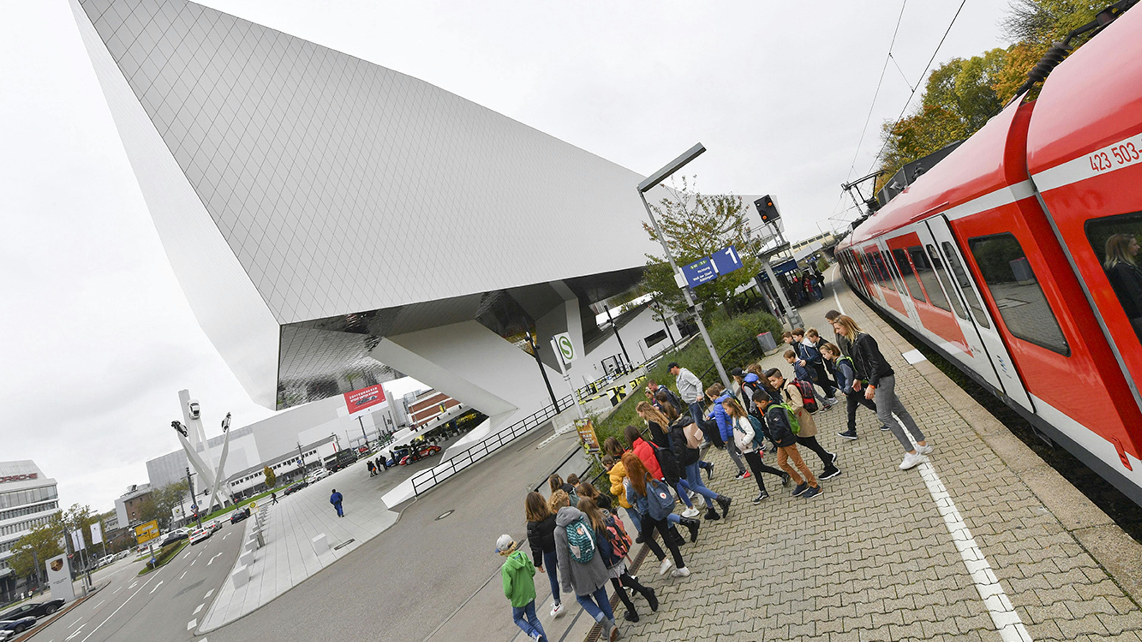 Eine Gruppe Kinder mit Begleitung kommt mit der Bahn zum Porsche Museum.