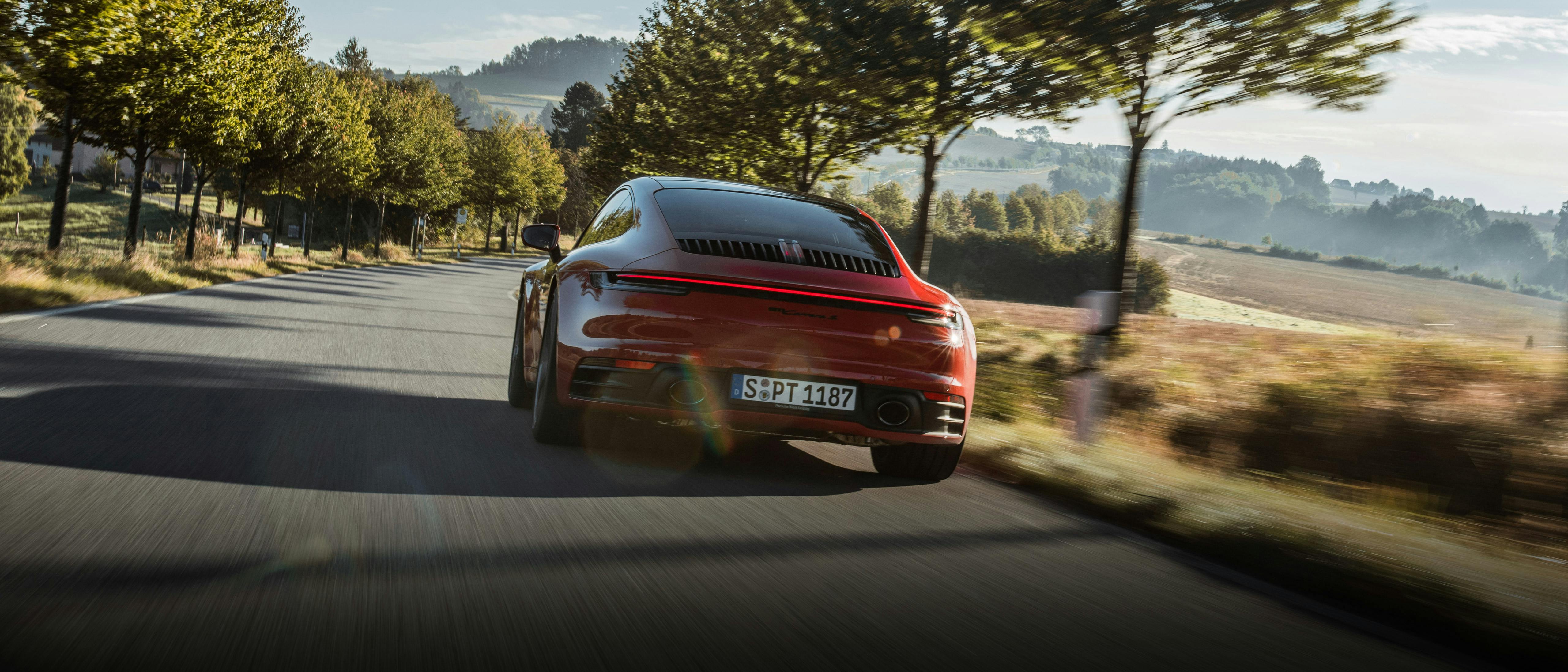 Porsche 911 Carrera S rouge traversant un paysage.