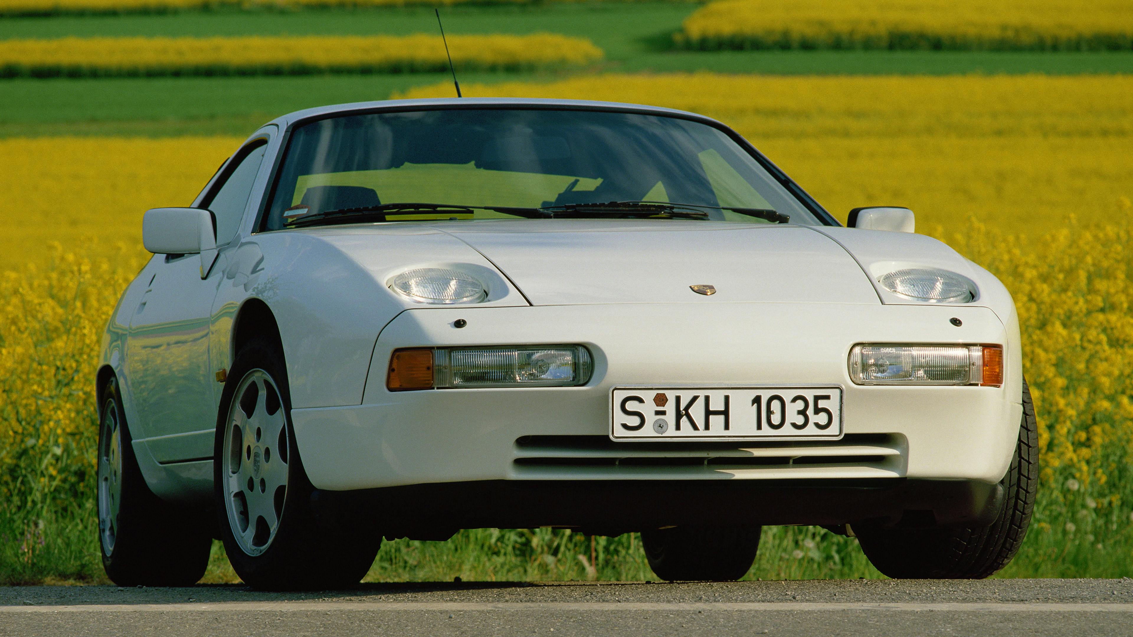 Weißer Porsche 928 GT vor gelbem Rapsfeldern.