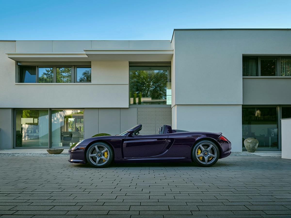 A Carrera GT coloured in Amthystmetallic from the side in front of a big modern house.