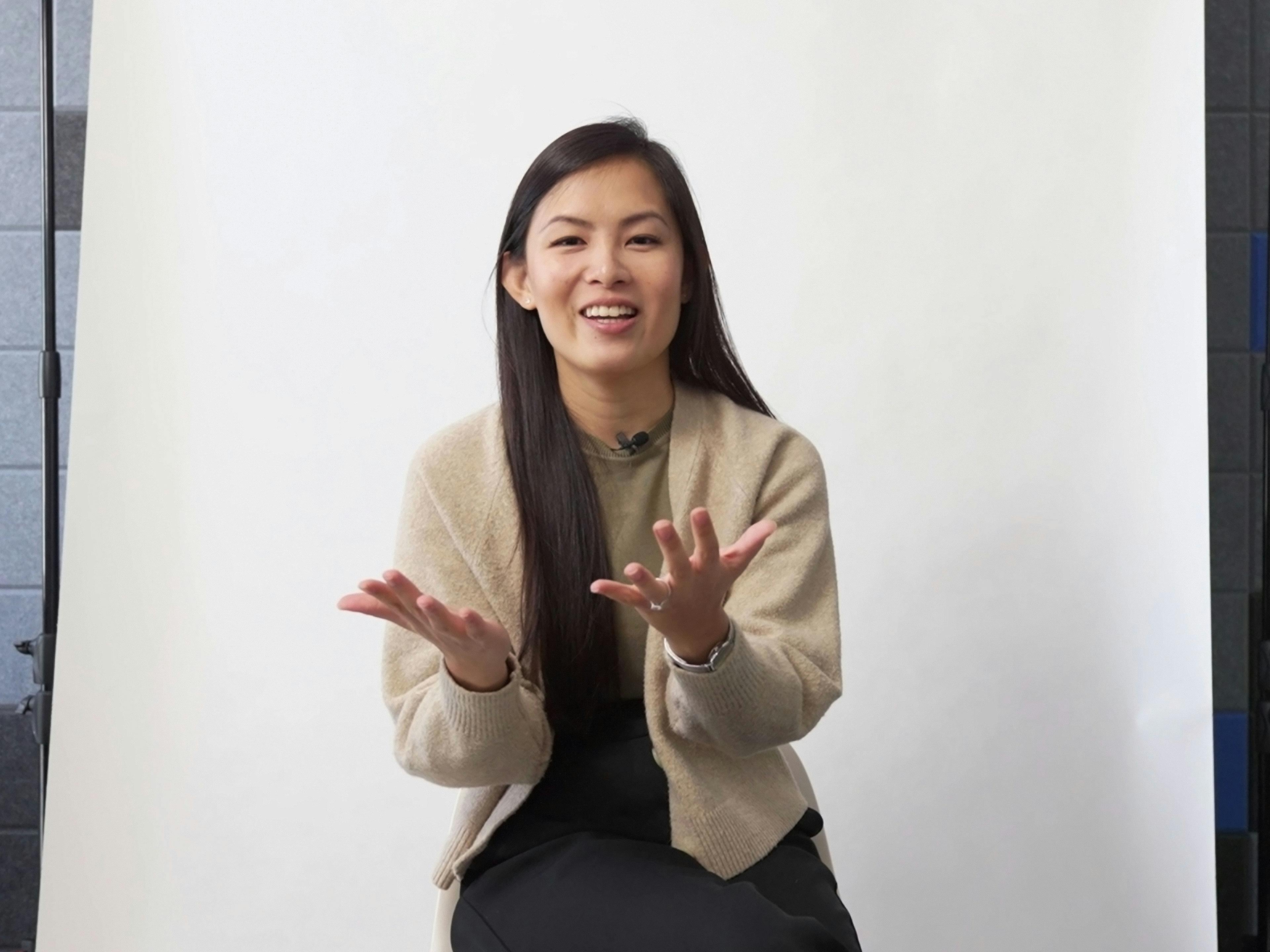 Porsche employee Sheena sitting in front of the camera in an interview and talking while gesturing.