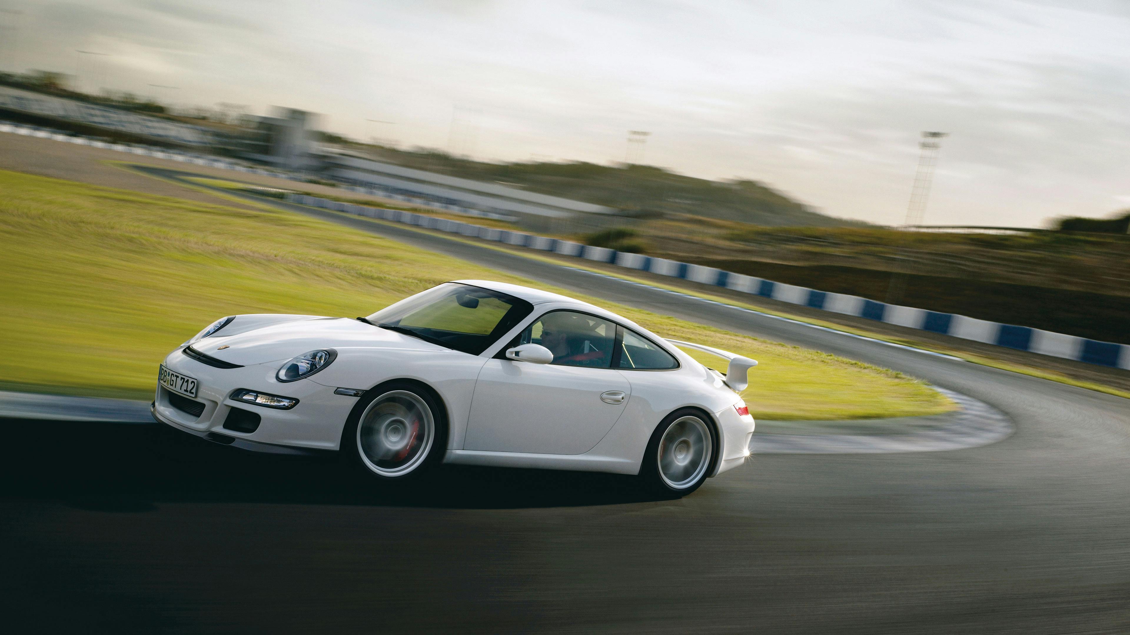 Driving white 911 GT3 type 997 on a race track.