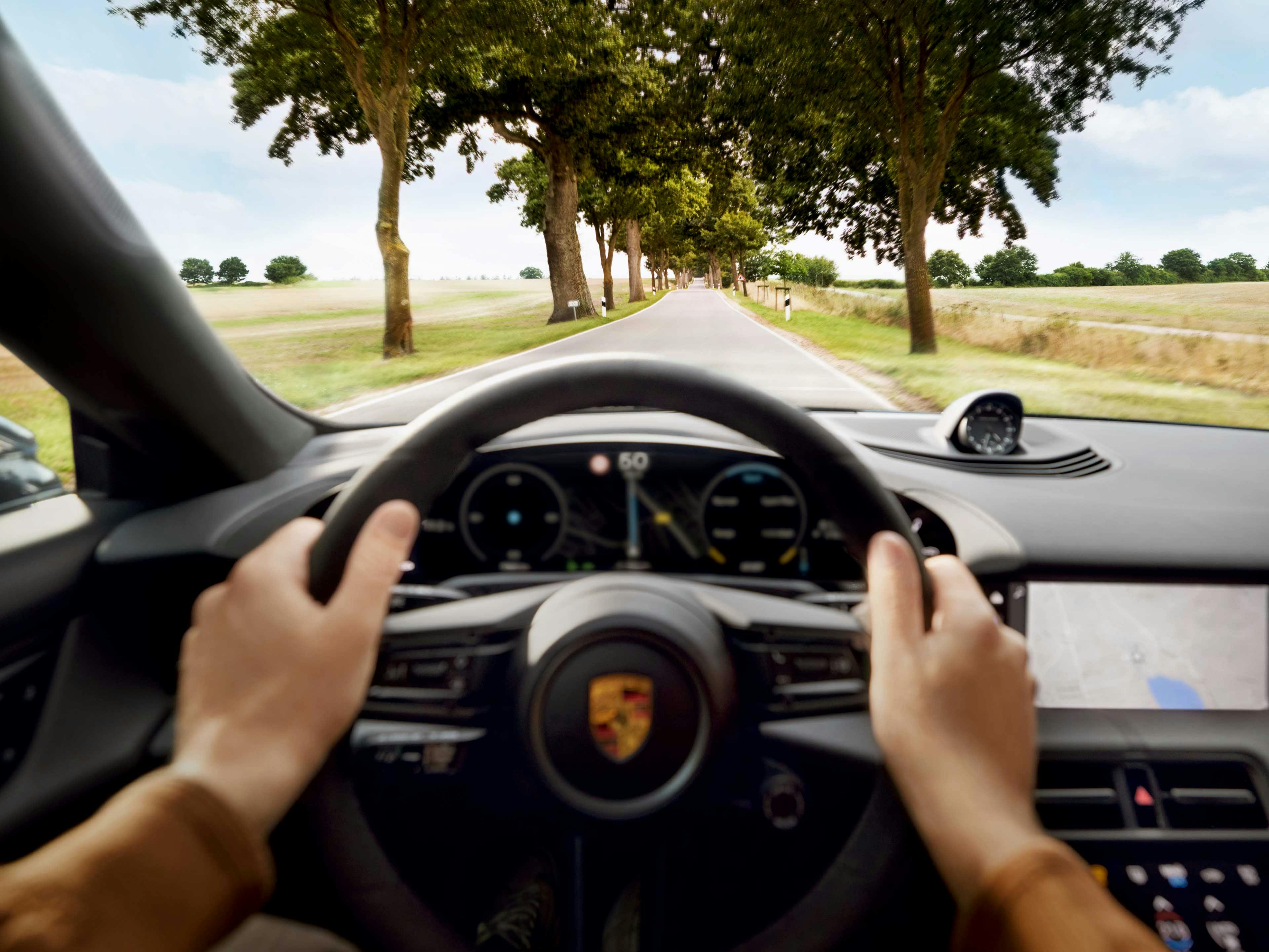 Inside view of a Porsche Taycan being driven through a countryside road.