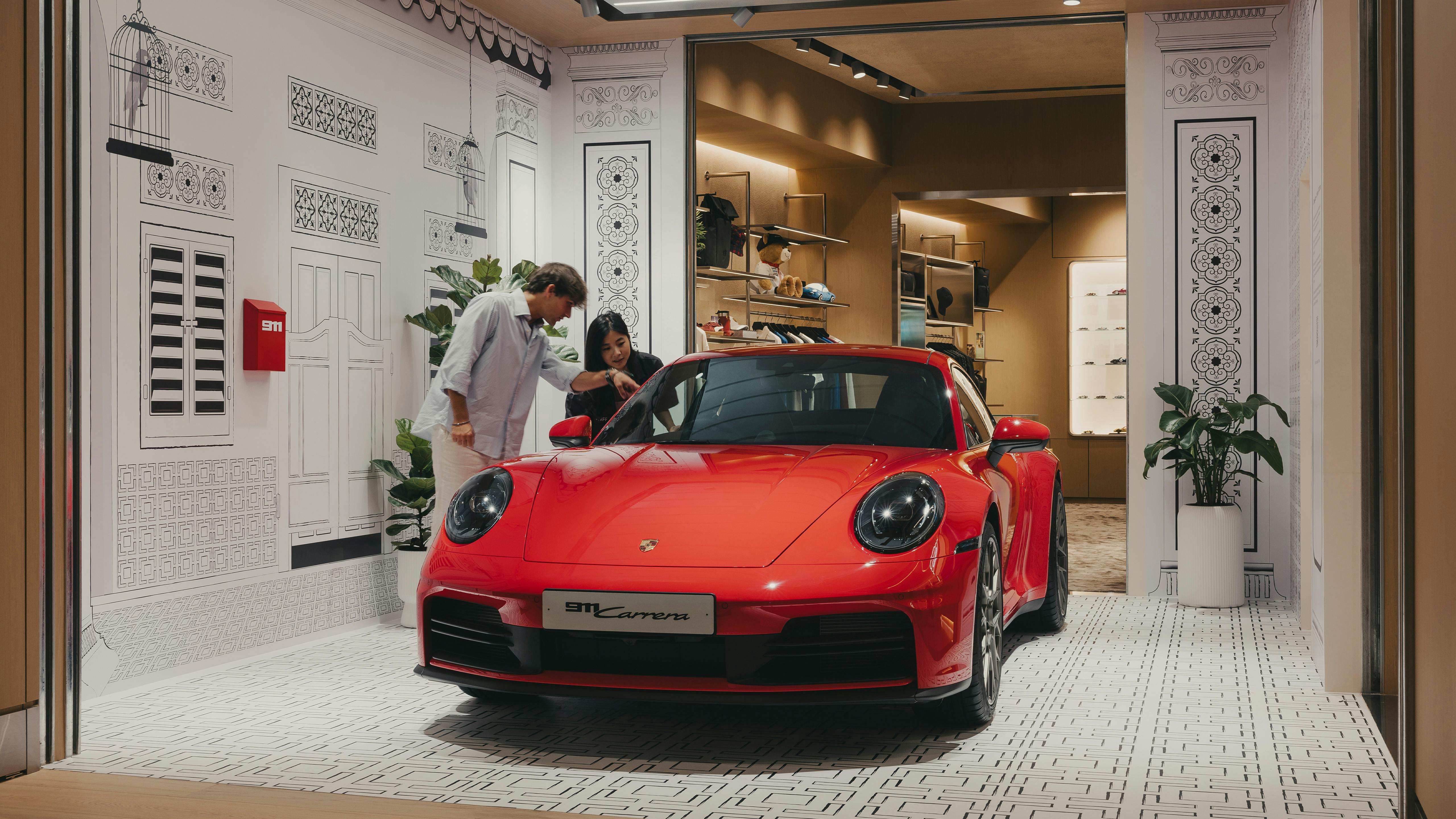 Couple admiring a Porsche 911 within the Porsche Culture Garage