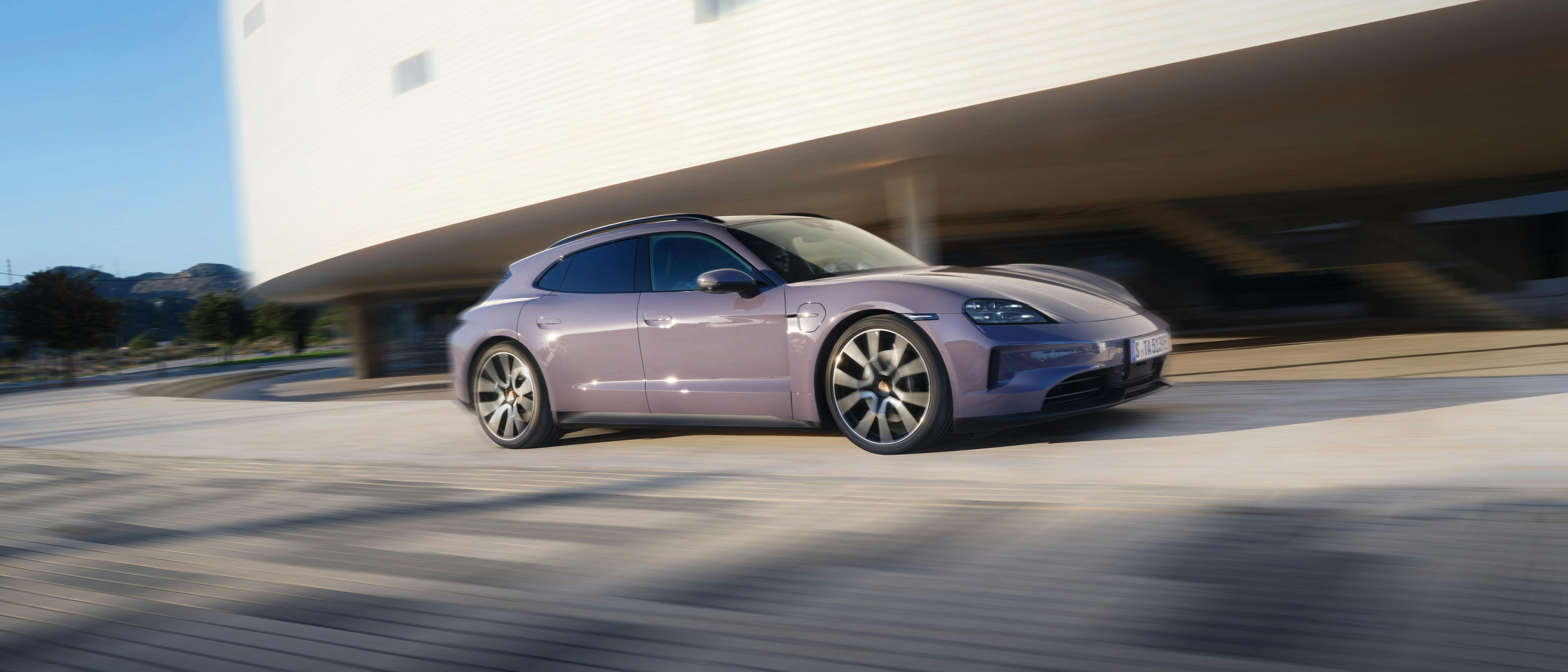 Taycan 4S Sport Turismo lors d'un trajet le long d'un bâtiment moderne.