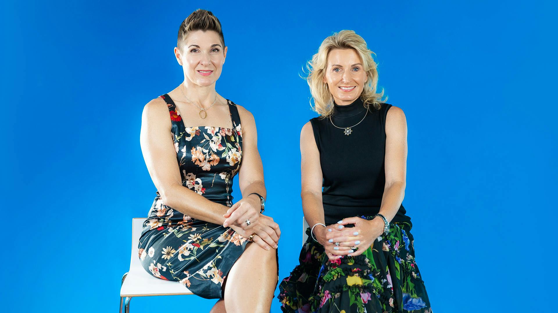 two women sitting infront of a blue background