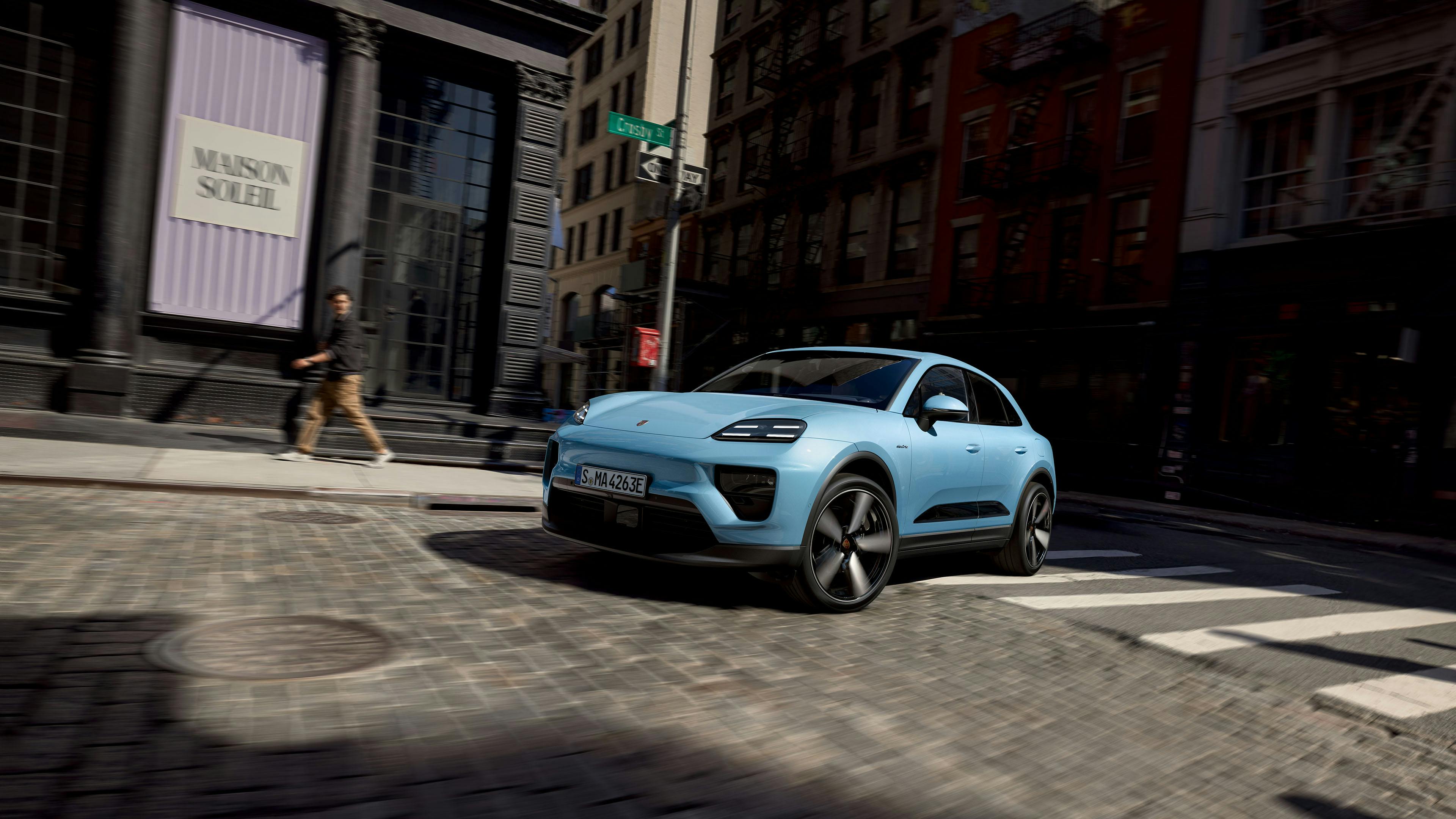 Een elektrische Porsche Macan rijdt door een straat in een stad.