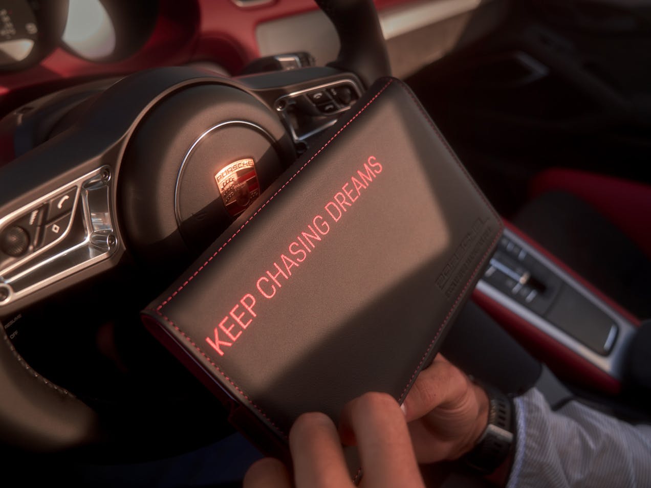 View of a Porsche Exclusive Manufaktur folder in front of a Porsche steering wheel.