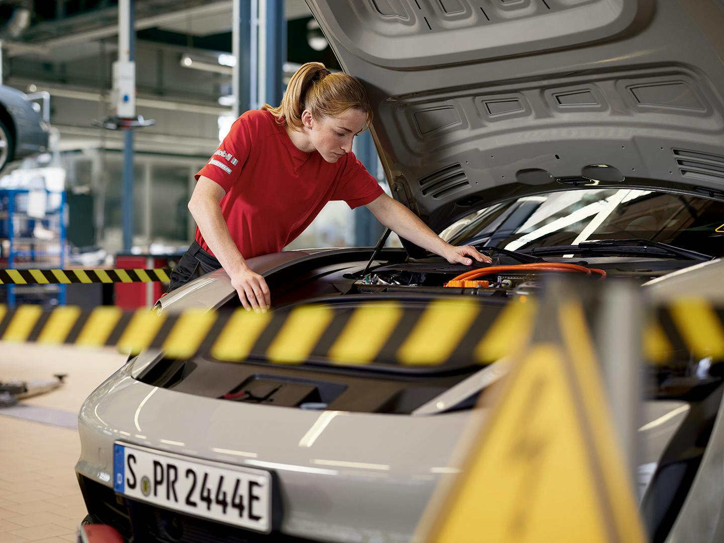 A woman conducting a high-voltage battery check on a Taycan.