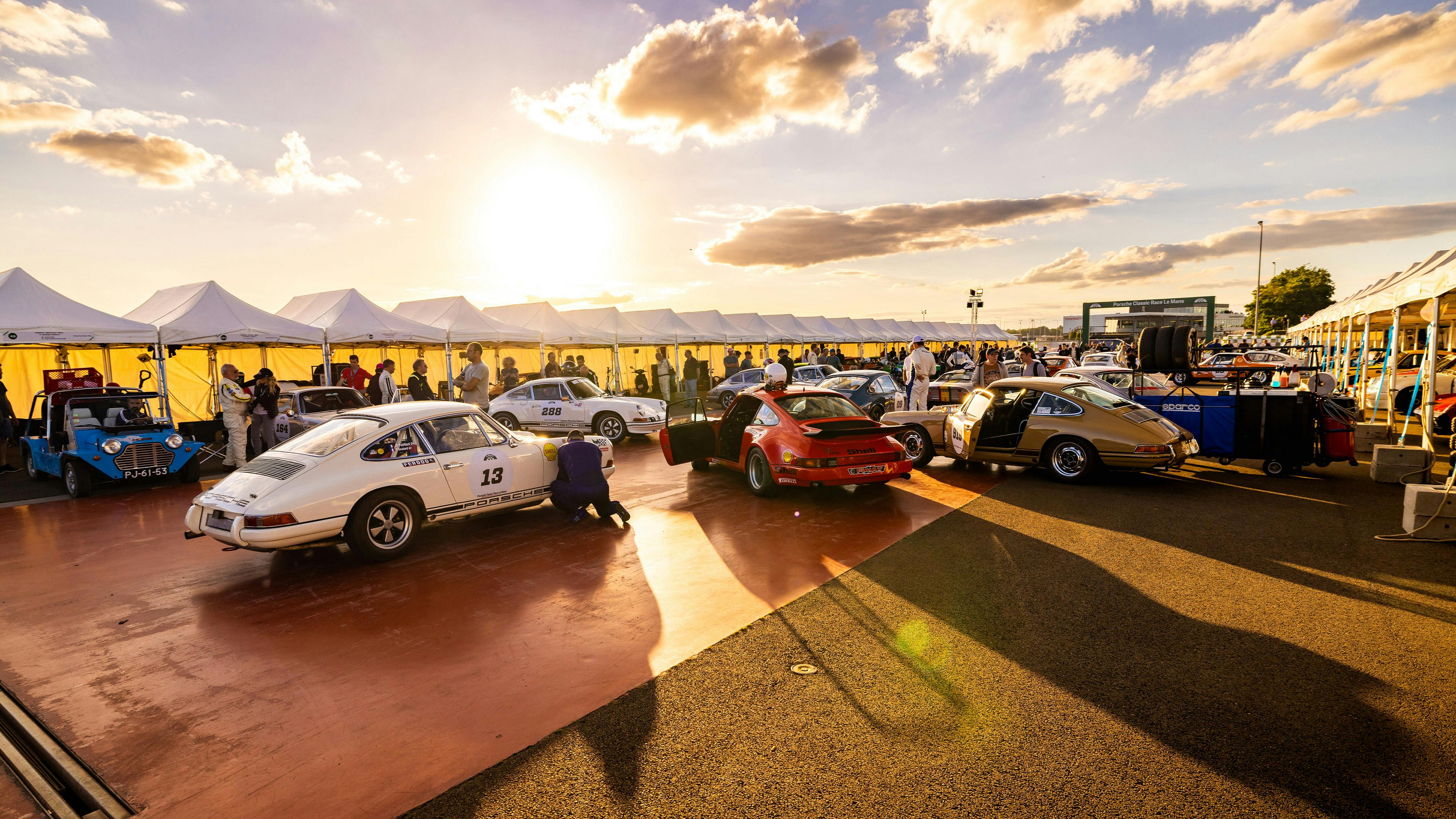 Porsche Club members with various Porsche Classic models are lined up on a promenade.