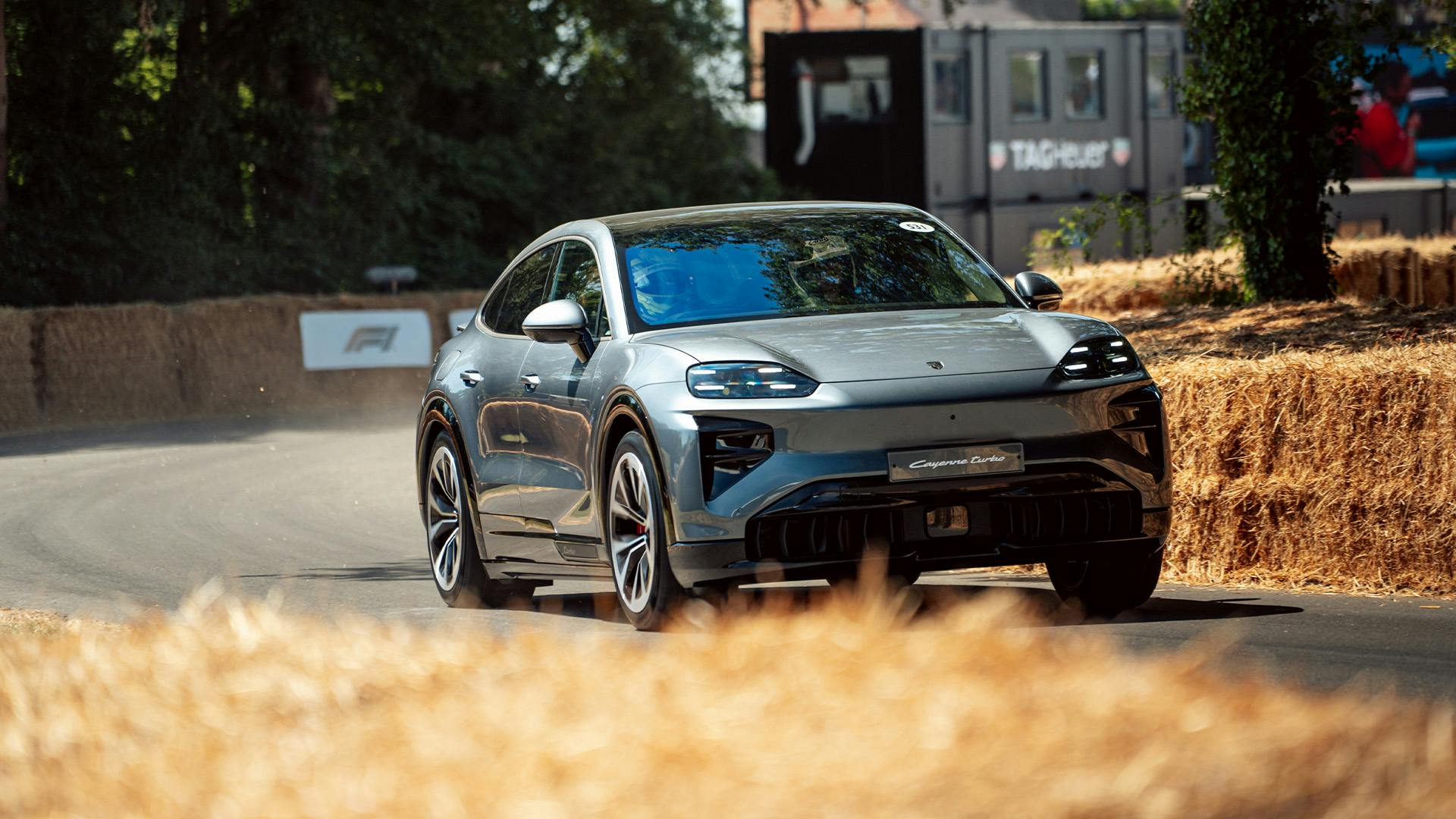 Porsche Macan Electric driving near grass at the Goodwood hillclimb.