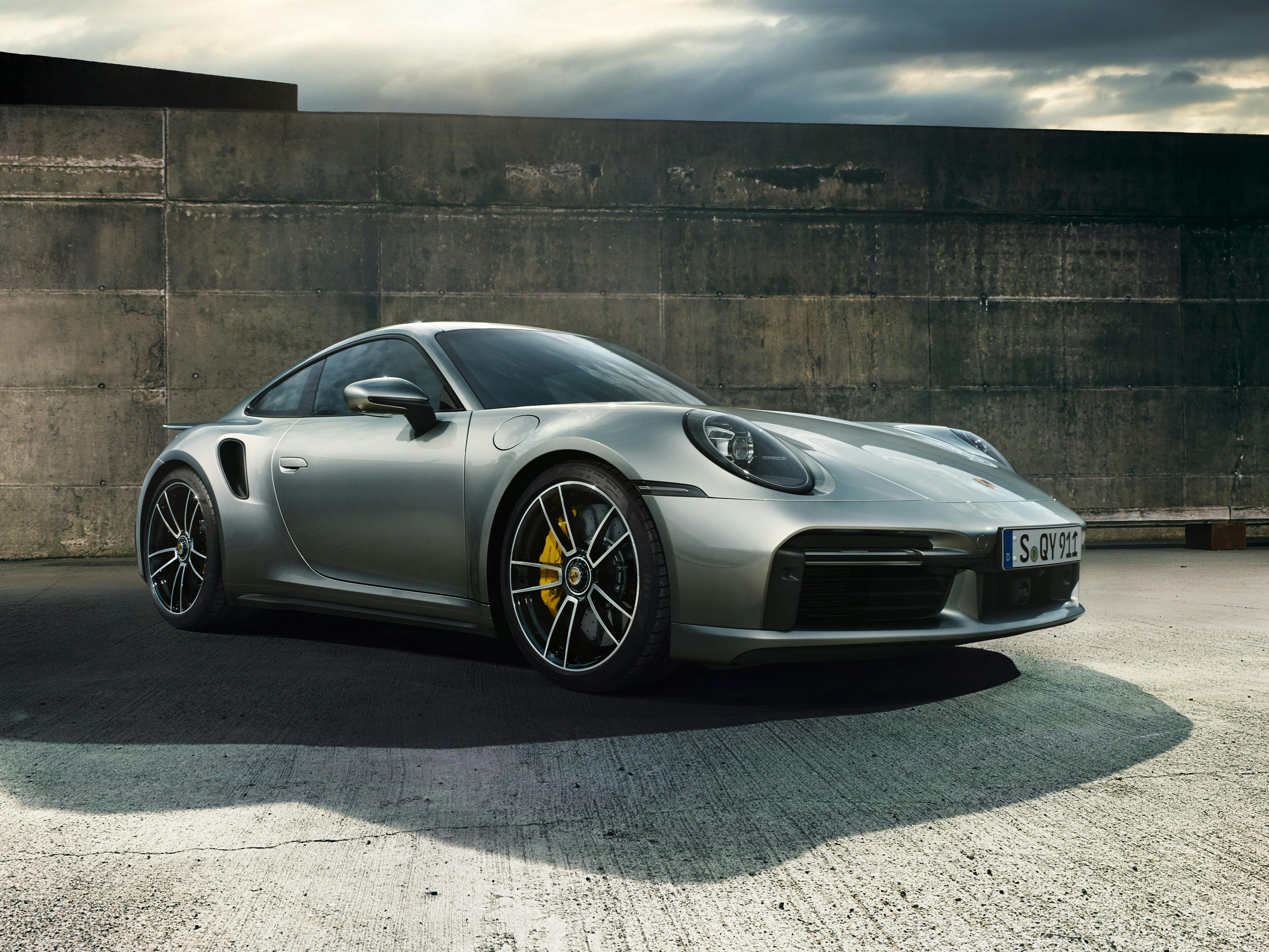 Ein silbener 911 Turbo S parkt vor einer Mauer.