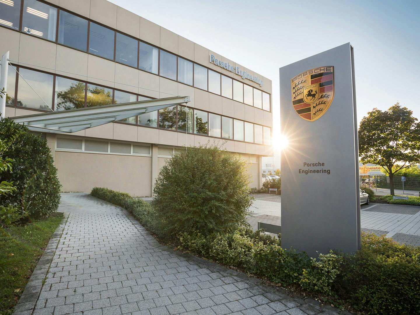 Haupteingang Standort Bietigheim-Bissingen mit Porsche Engineering Firmenschild vor dem Eingang.