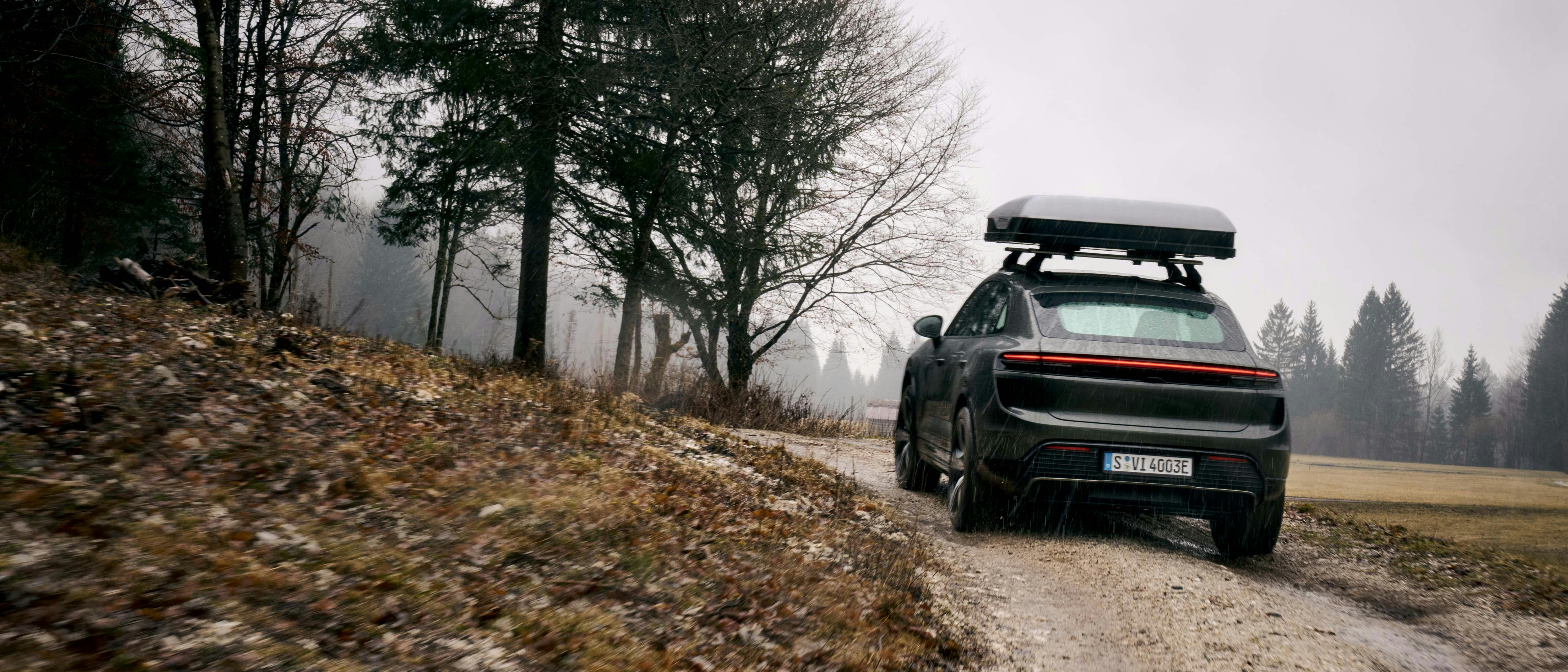 Een Porsche Macan rijdt door de bergen met een daktent